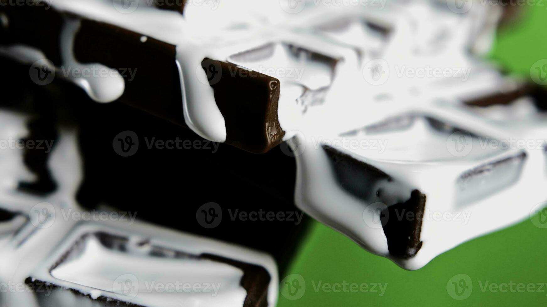 Close up of contrasting dark chocolate bar and trickling sweet white chocolate glaze. Stock clip. Delicious chocolate on a green chroma key background. photo