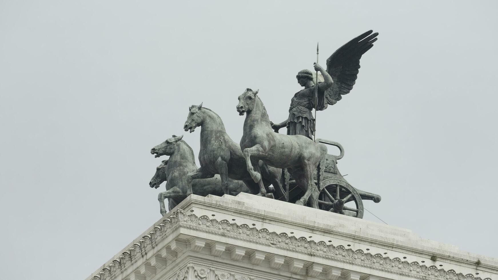 Italy, Rome - July 29, 2022. Statue with horses and man on building. Action. Beautiful composition with statues on roof of old building. Sculptural statues on ancient architectural building on photo