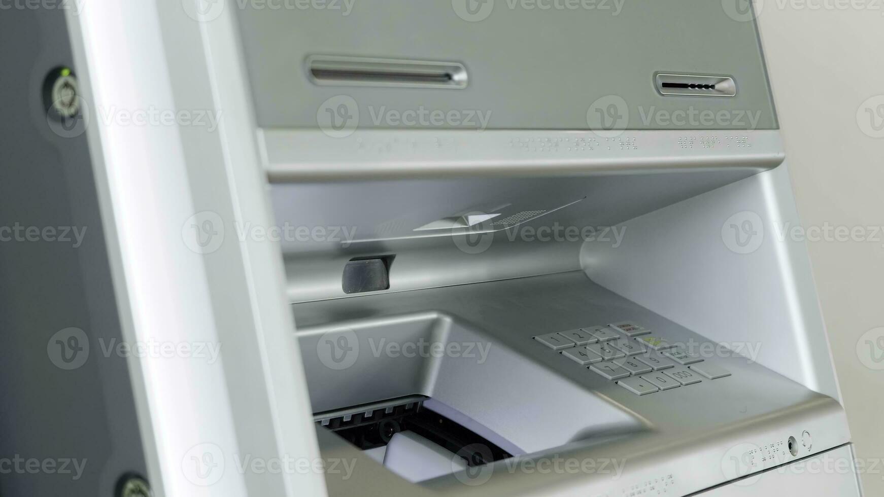 ATM bank machine and male hand performing financial transactions. HDR. Close up of man putting money inside a bank machine. photo