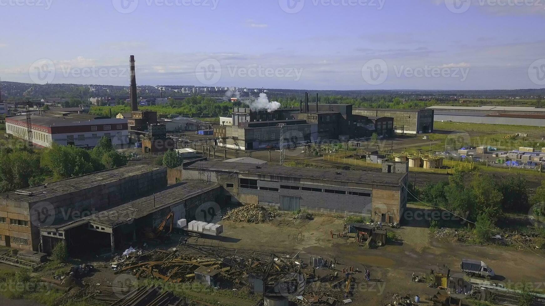 ver de el trabajo zona desde el zumbido. acortar. un grande fábrica con tubería desde cuales fumar es próximo, el ciudad y el bosque y el calma cielo son visible desde detrás. foto