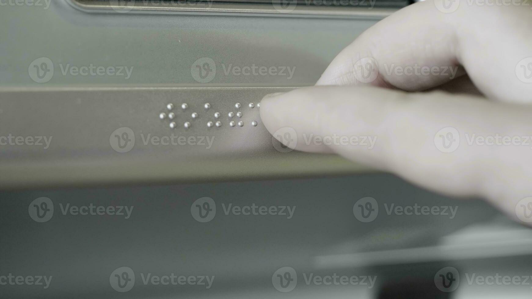 Close up of male hand touching Braille on a metal sign. HDR. Visually impaired or blind person using hand to read information on a metal sign. photo