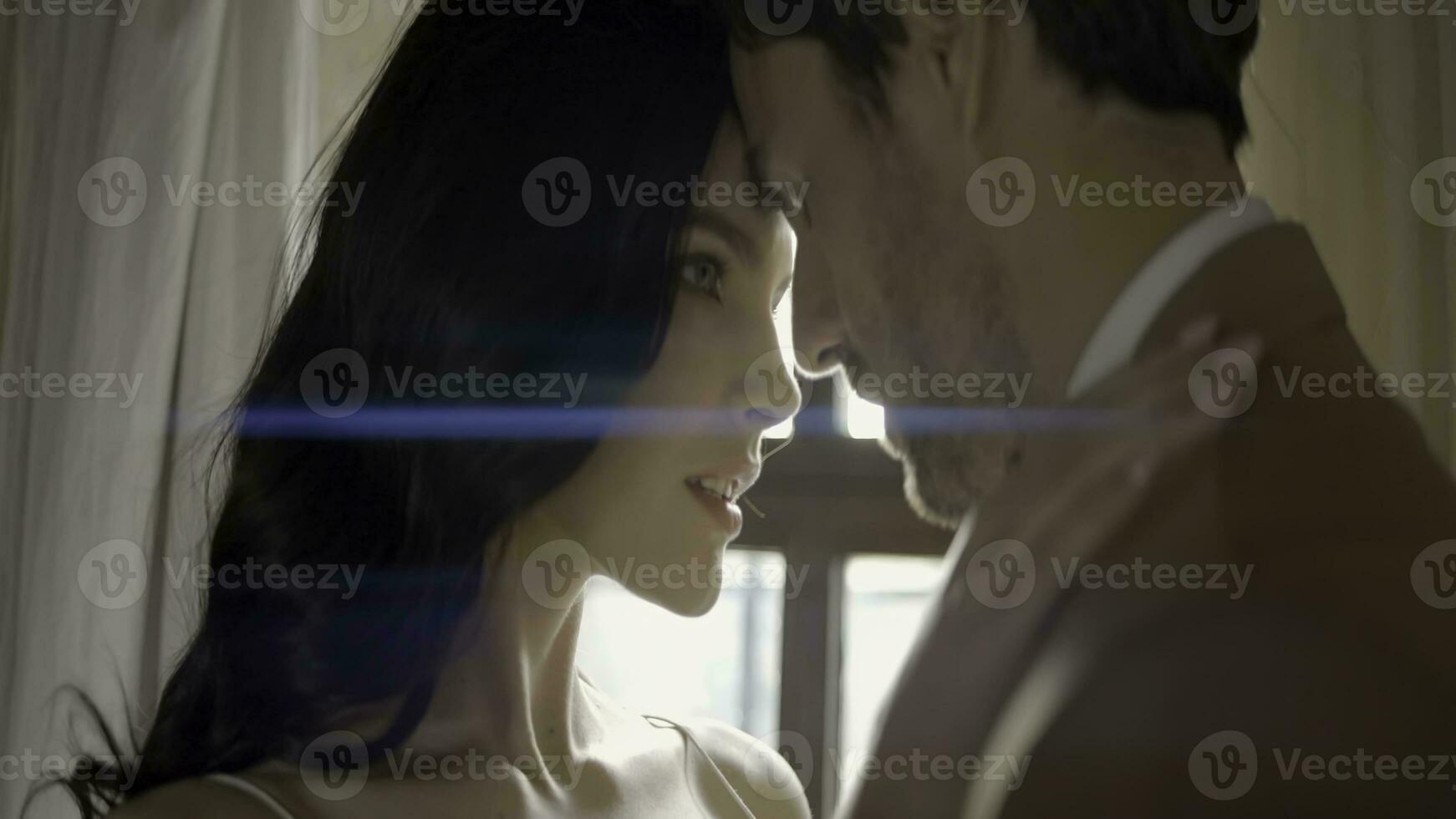 Newlyweds embrace on background of window. Action. Beautiful newlyweds passionately look at each other at bright window. Close and passionate views of newlyweds photo