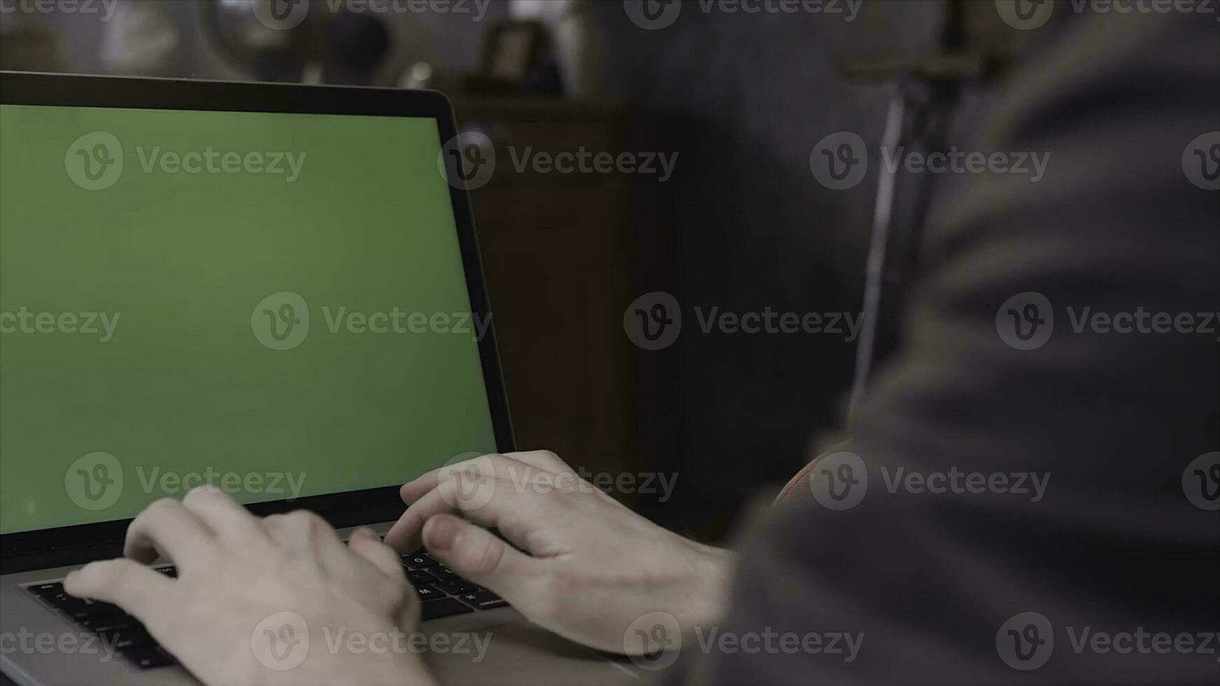 Close up rear view of young businessman hands typing on a laptop keyboard with a blank green editable screen. Stock footage. Man using laptop with chroma key. photo
