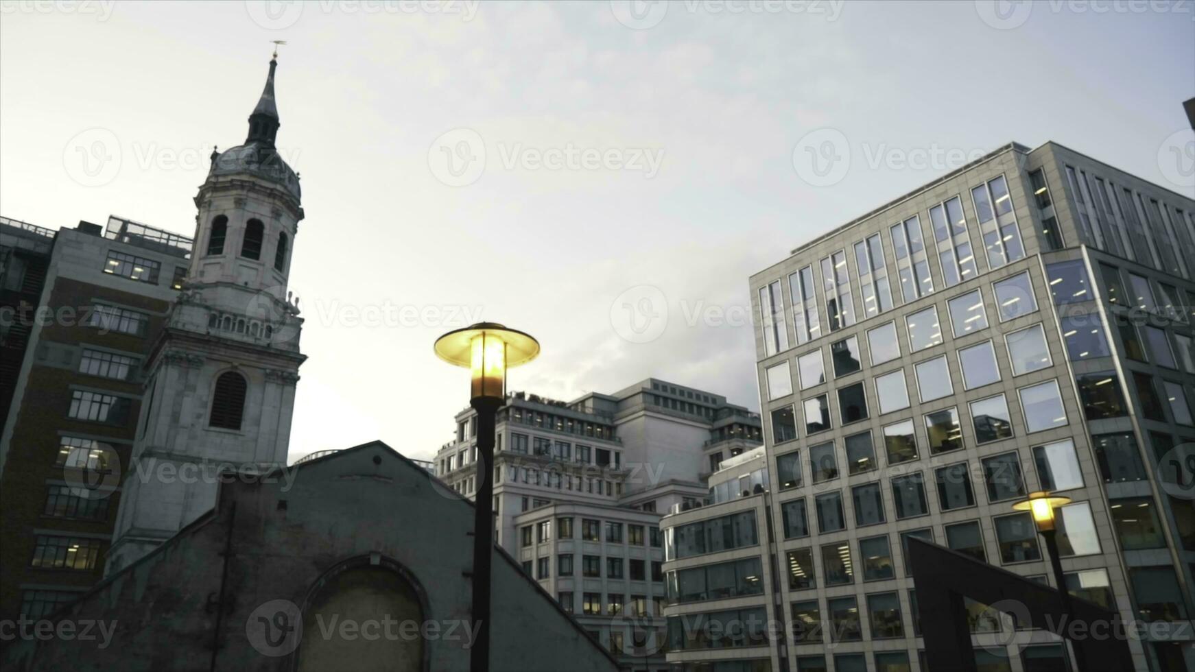 Close-up of yellow street lights in the center of London near the modern glass skyscrapers against the blue evening sky. Action. Evening city scenery photo