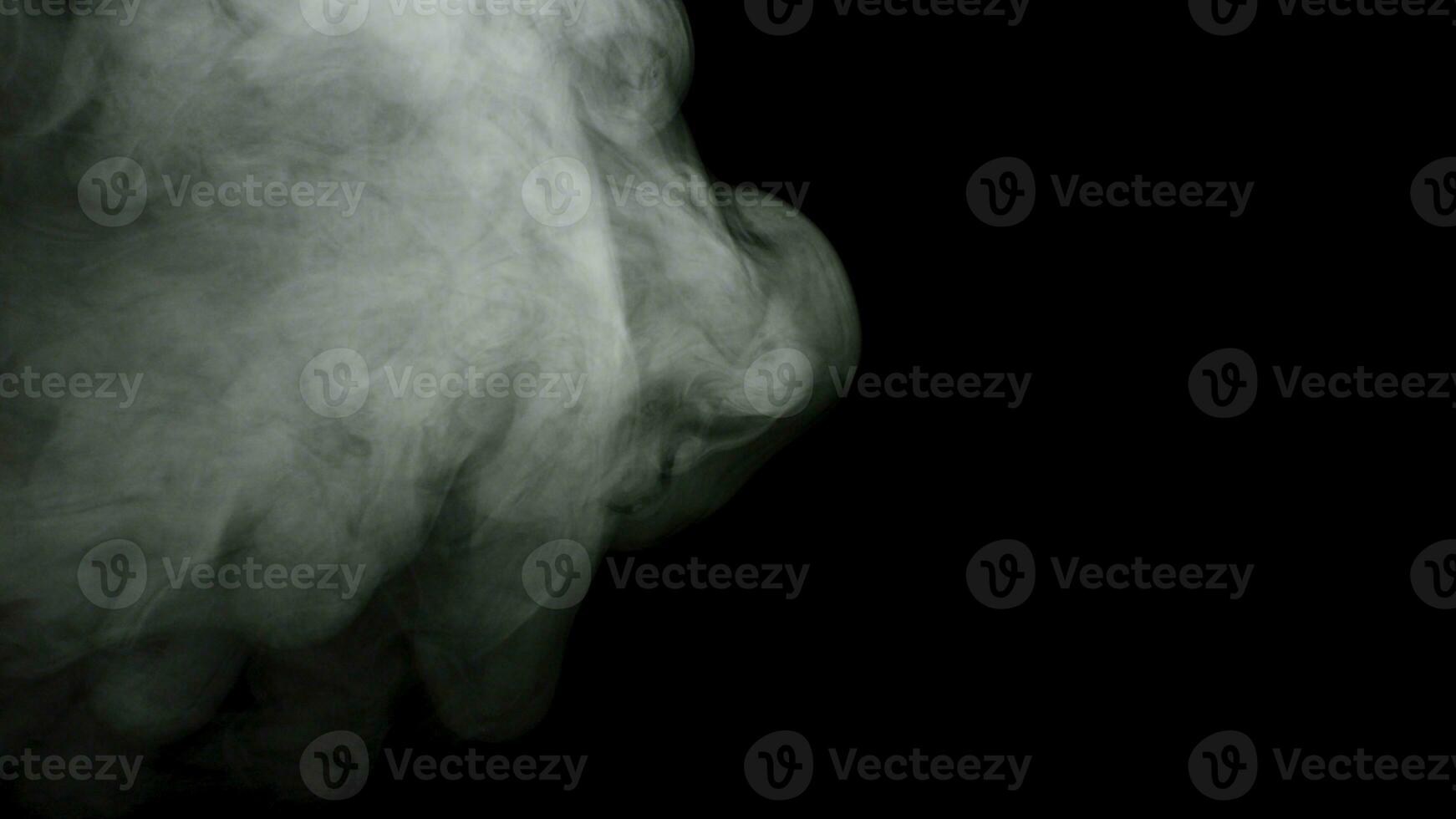 Abstract fog or smoke soaring and spreading over black color background. Stock footage. White puffs of smoke moving slowly in the dark. photo