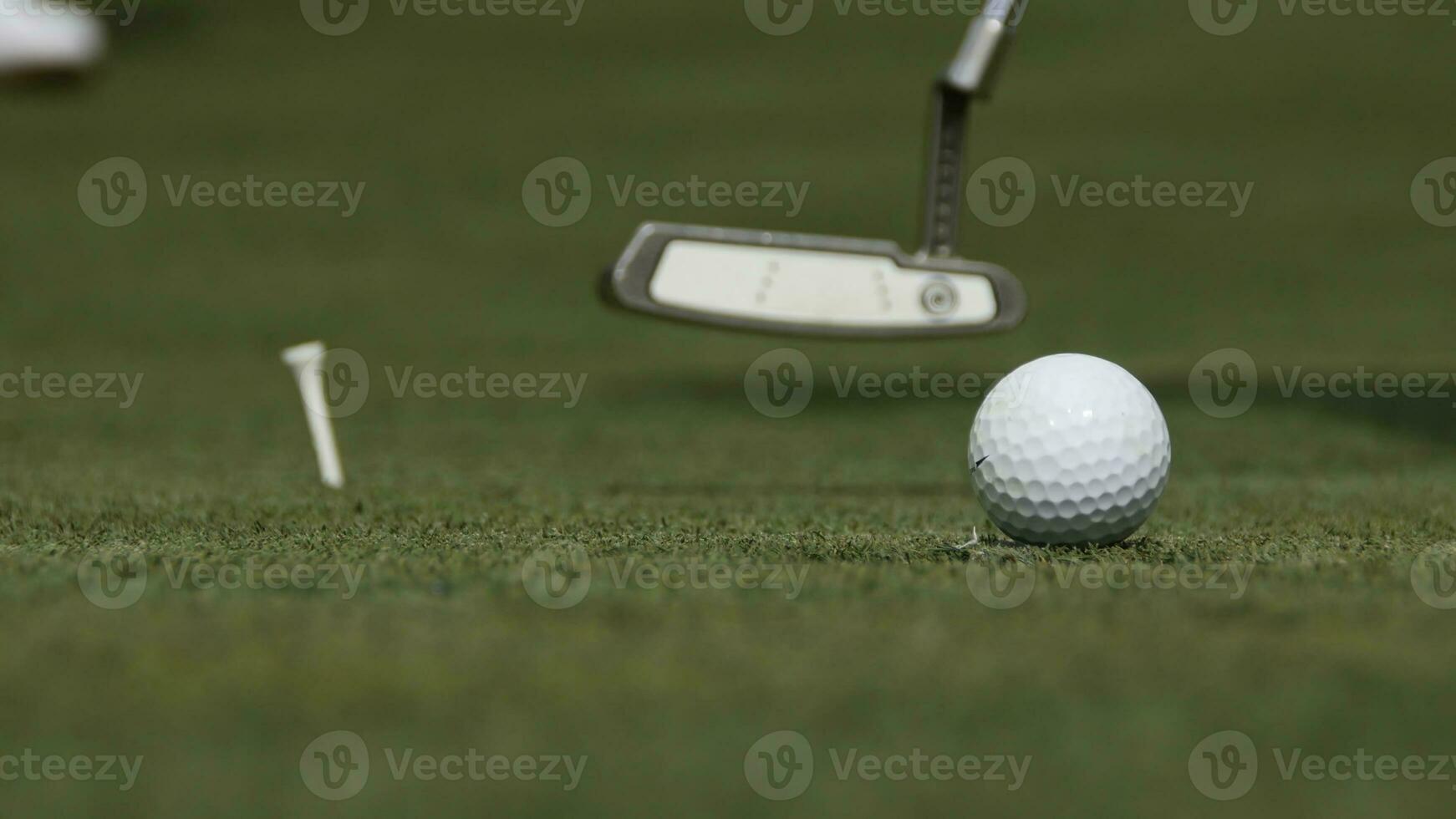 Professional golfer putting ball into the hole. Golf ball by the edge of hole with player in background on a sunny day photo