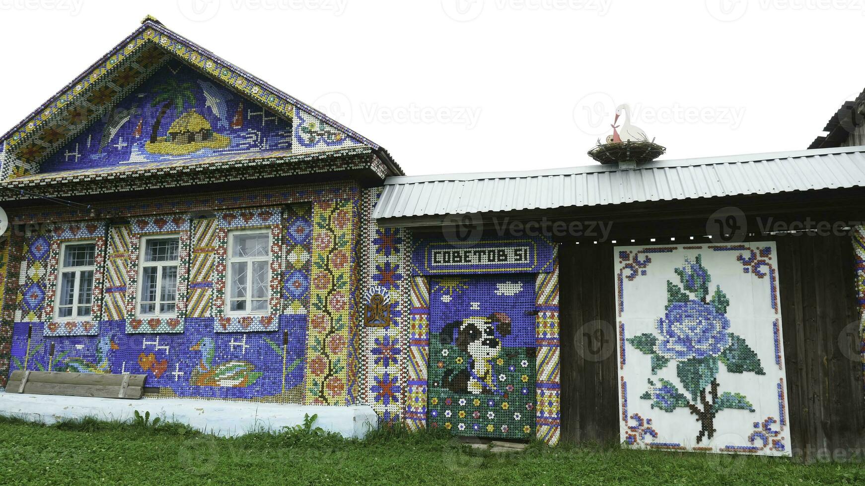 Unusual facade an old wooden house decorated by colorful mosaic pictures from small plastic bottle caps, creativity concept. Stock footage. Beautiful and bright hand made mosaic wall. photo