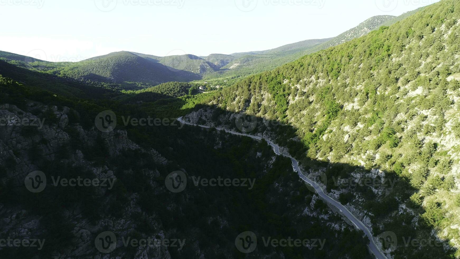 Aerial view of road going through a green mountains covered with shrubs and grass against blue sky in subber day. Shot. Beautiful view from above photo
