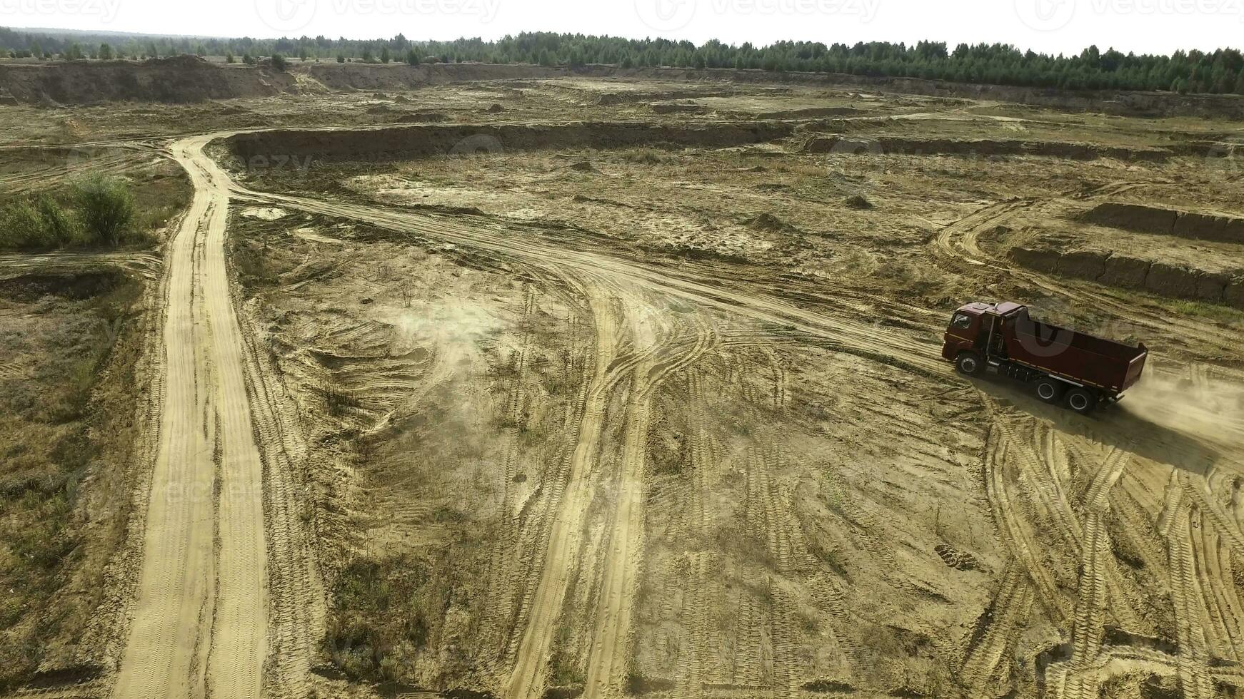 Truck rides on sand quarry road. Scene. Top view of dump truck driving on yellow dirt road in countryside. Large trucks on construction or quarry terrain photo