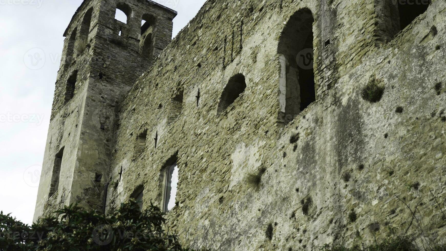 Bottom view of ancient fortress wall on background of sky. Action. Crumbling medieval stone fortress serves as tourist attraction in Europe photo