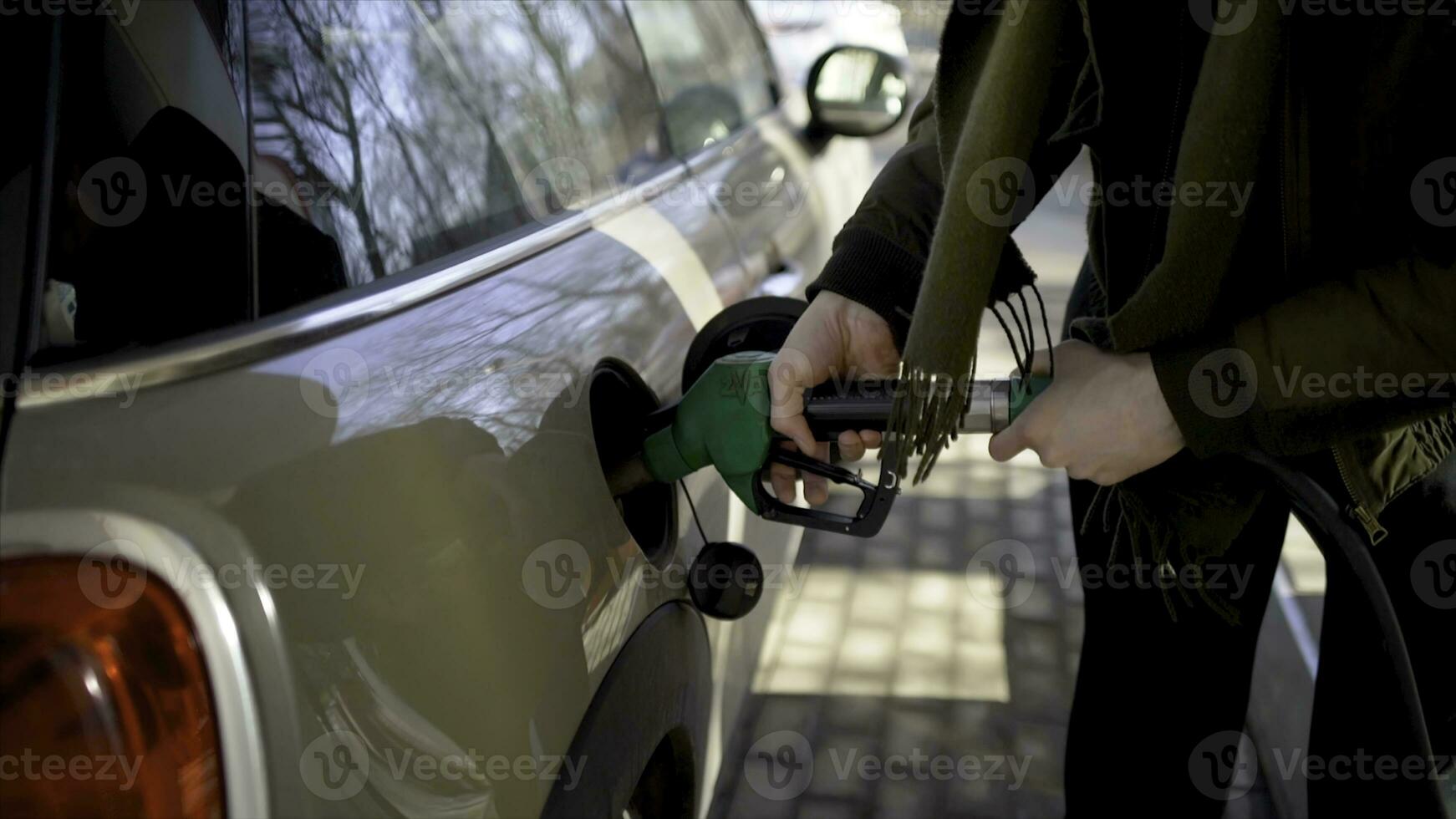 Man inserts hose into car at gas station. Action. Man nervously and quickly refuels car at gas station. Filling up car during long chase photo