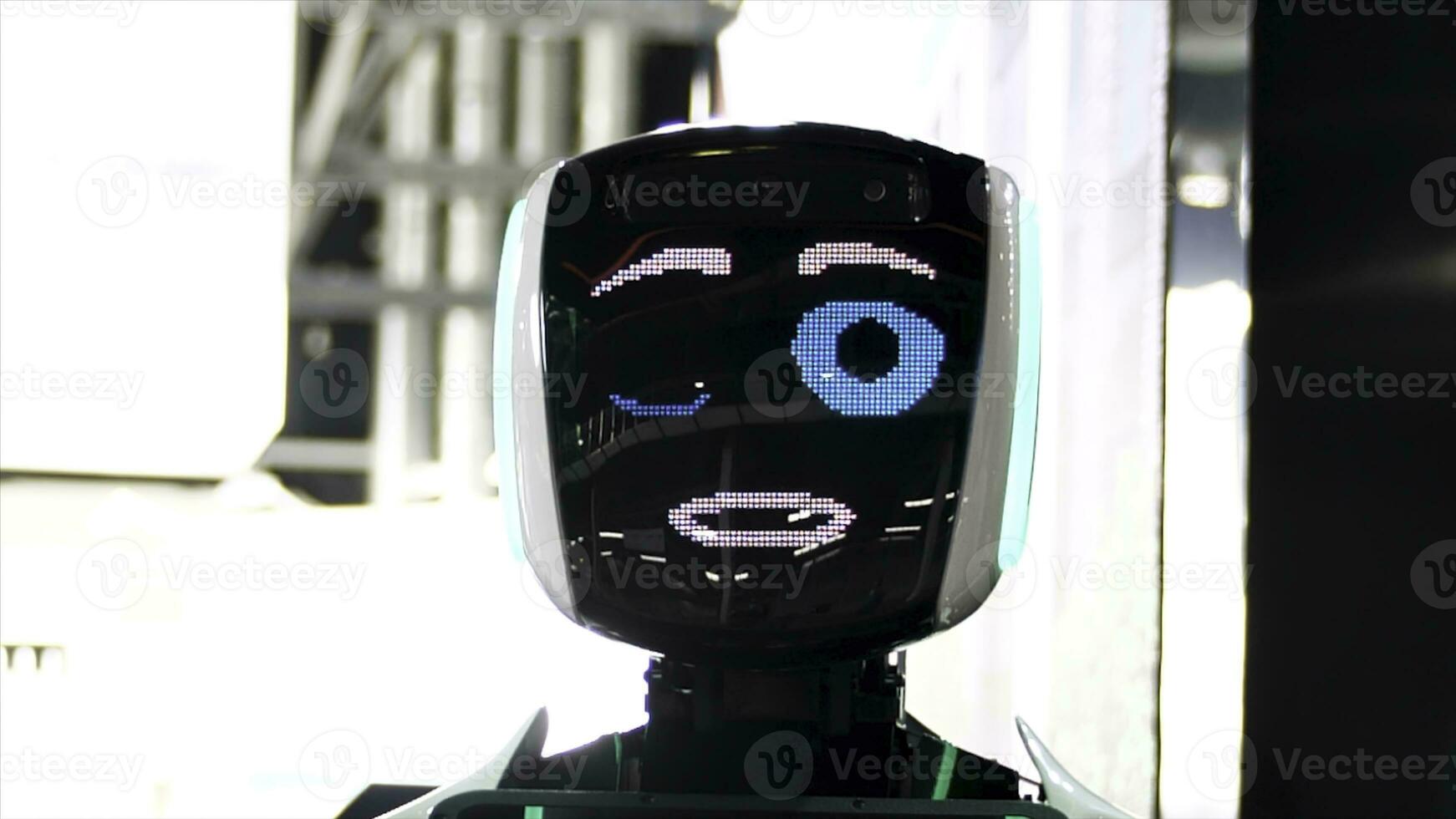 Funny robot with big blue eyes smiling, talking, and winking . Meida. Close up of robot face screen with friendly smile at the exhibition of modern technologies. photo