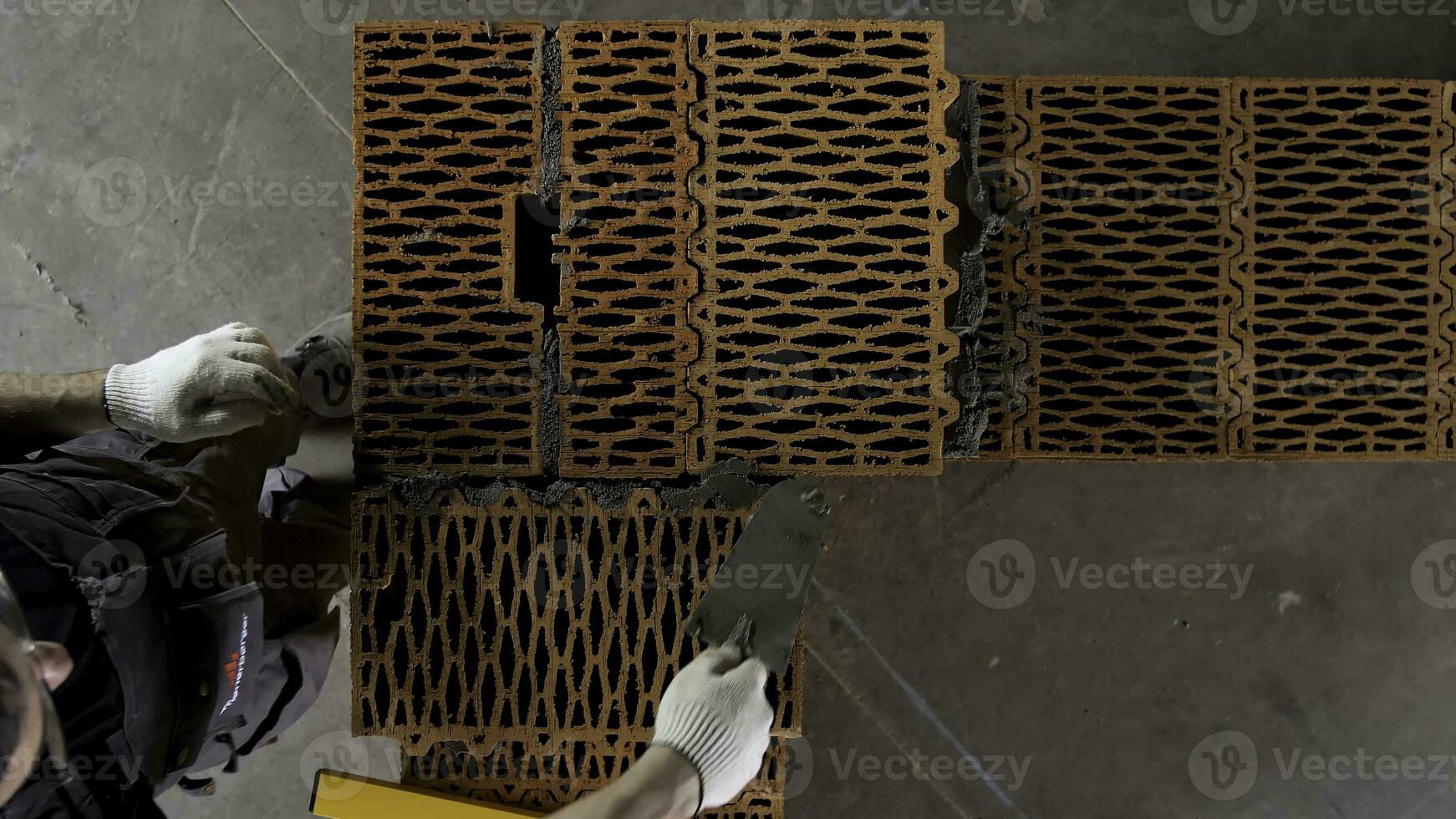Bricklayers hands with in masonry trowel bricklaying new house wall on foundation. Stock footage. Bricklayer and mason working with bricks and building interior. photo