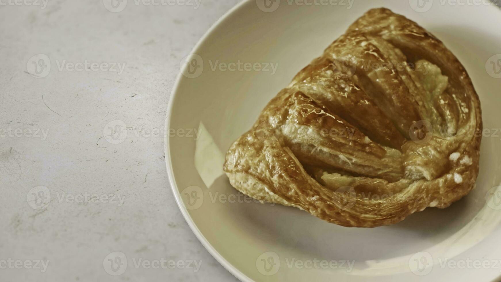 Close up top view of real sweet and fresh bun lying on the plate on white table background. Stock footage. Perfect breakfast, foodporn concept. photo