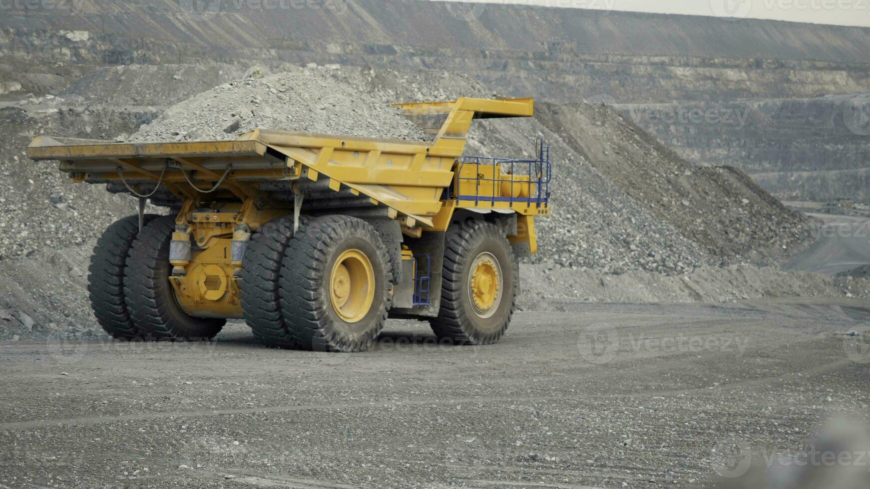 Close-up of dump truck moving on a quarry road loaded with ore. Back view. photo