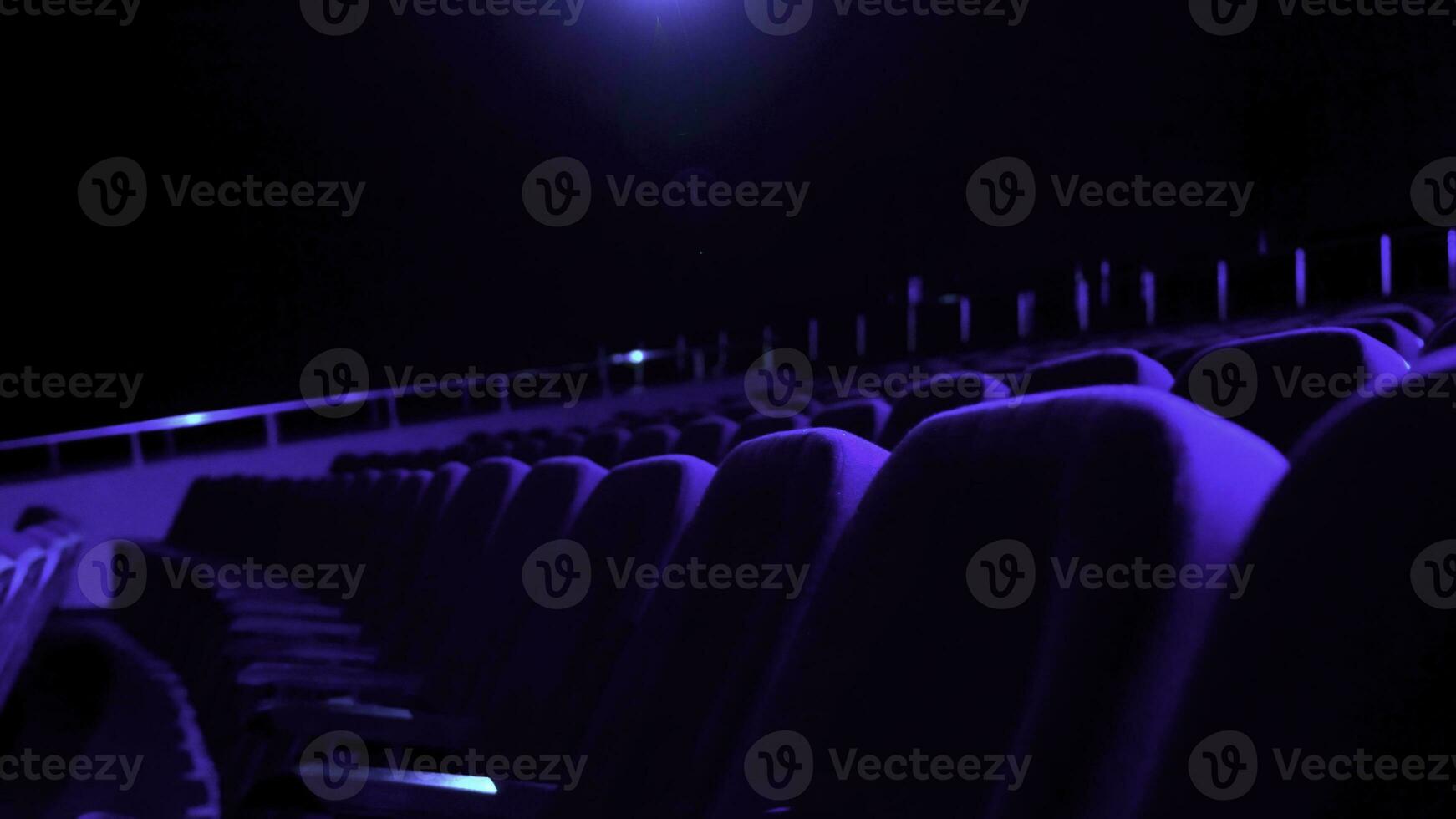 Dark, empty cinema hall with comfortable seats in blue light. Close up for seat rows in movie theatre. photo