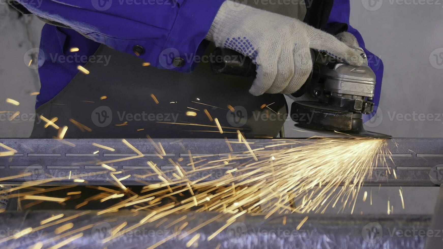 Craftsman sawing metal with disk grinder in workshop. Grinding metal with sparks flying. Electric wheel grinding on steel structure in factory Low speed shutter. Metal grinding with orange flying photo
