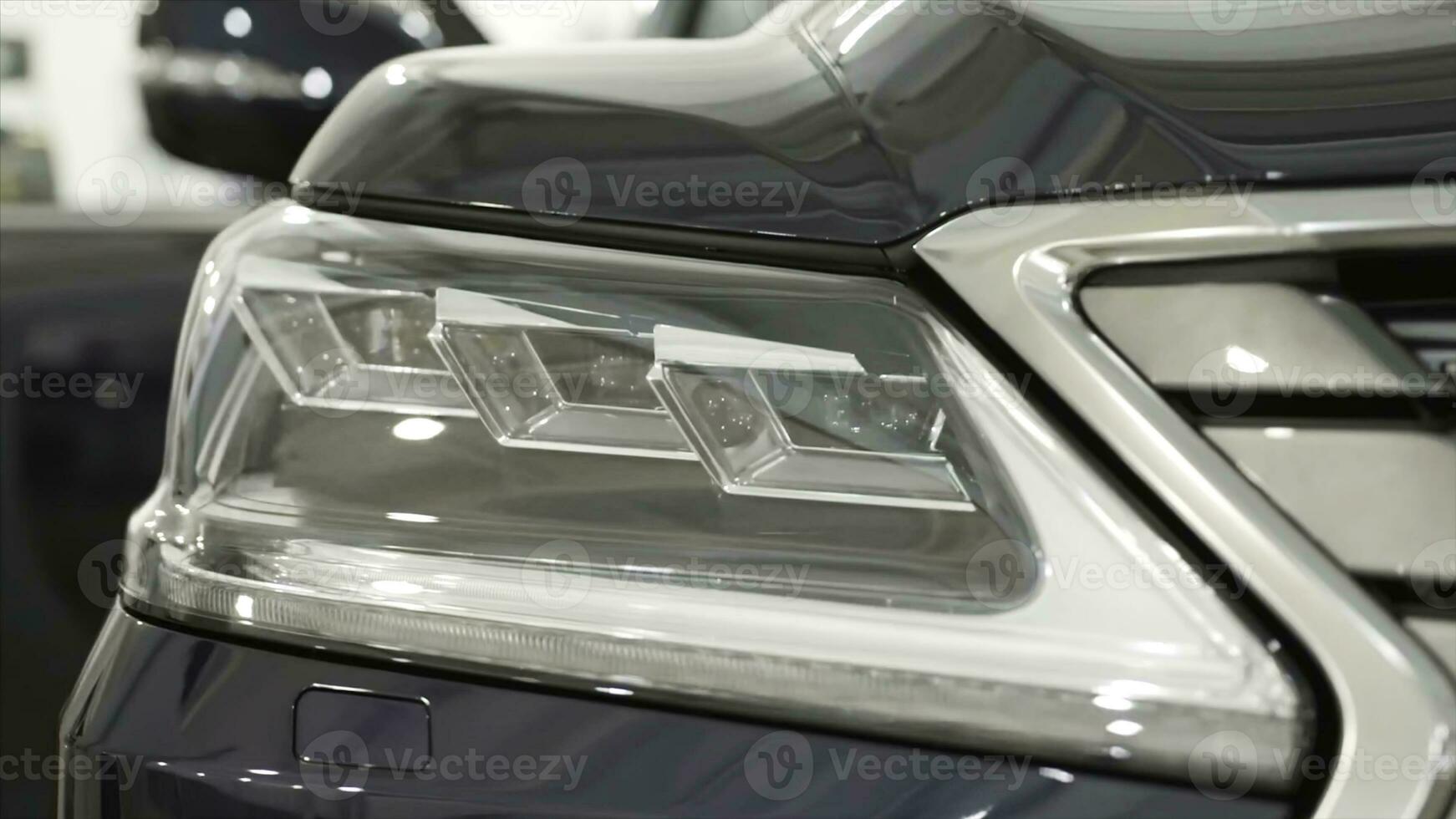 Close up for the headlights of the black new, polished car, luxury concept. Action. Modern car headlights parked in a dealer showroom. photo