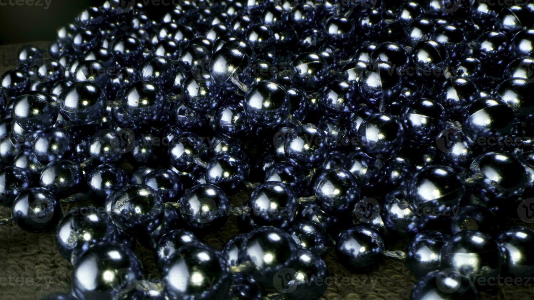 Close up of blue beads garland lying on the carpet. Stock footage. Decorative background with shining beads garland, concept of Christmas and New Year winter holidays. photo