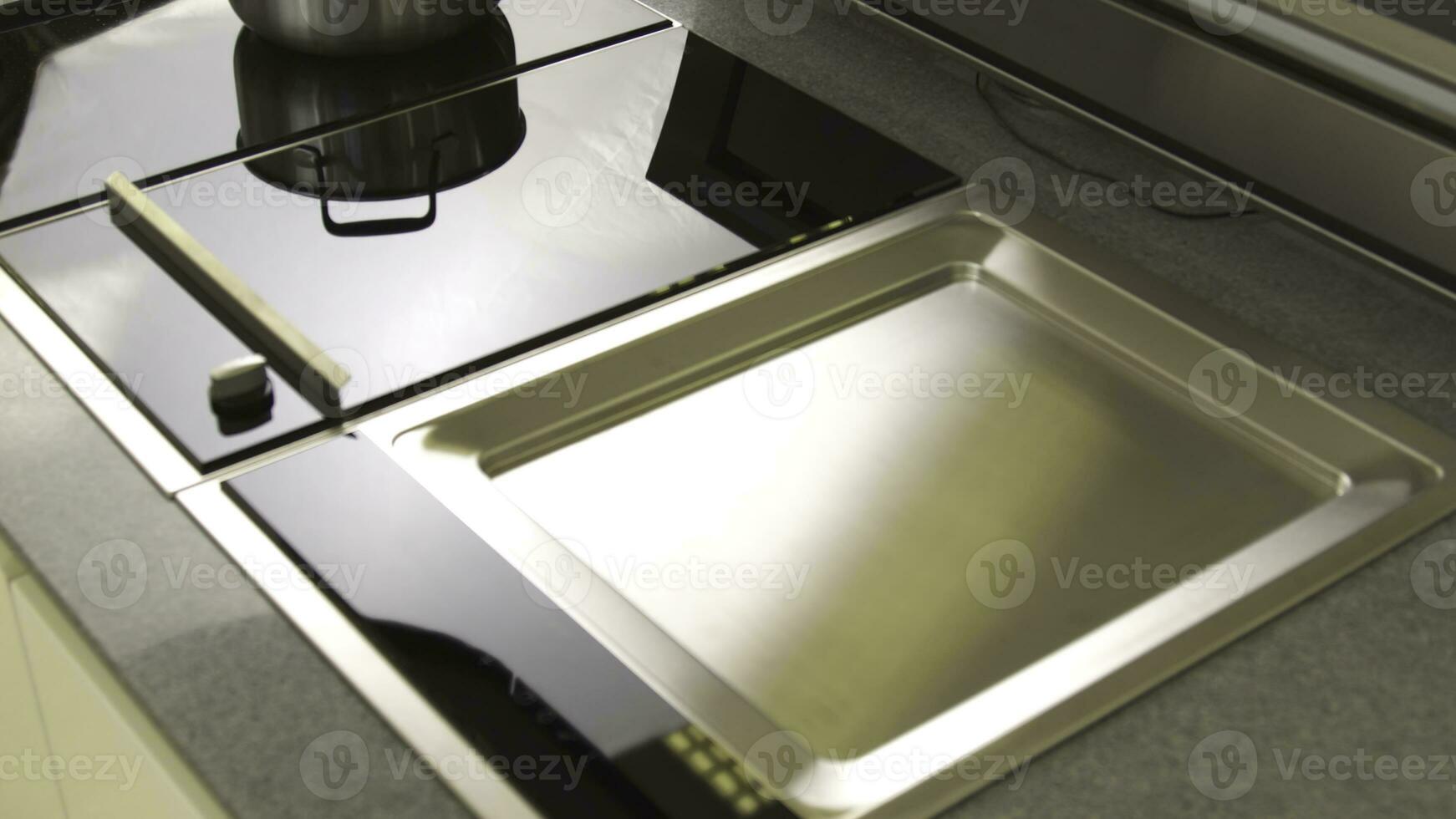 A freshly cleaned glass surface of an electric cooker built into the kitchen worktop. Household utensils. Close up view of high tech kitchen details. photo