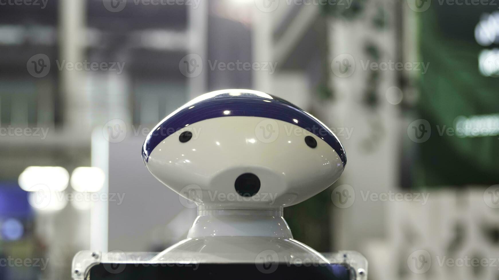 Close up of the moving humanoid robot with a camera on his head. Media. New technological robot moving at the exhibitional center, technologies of the future. photo