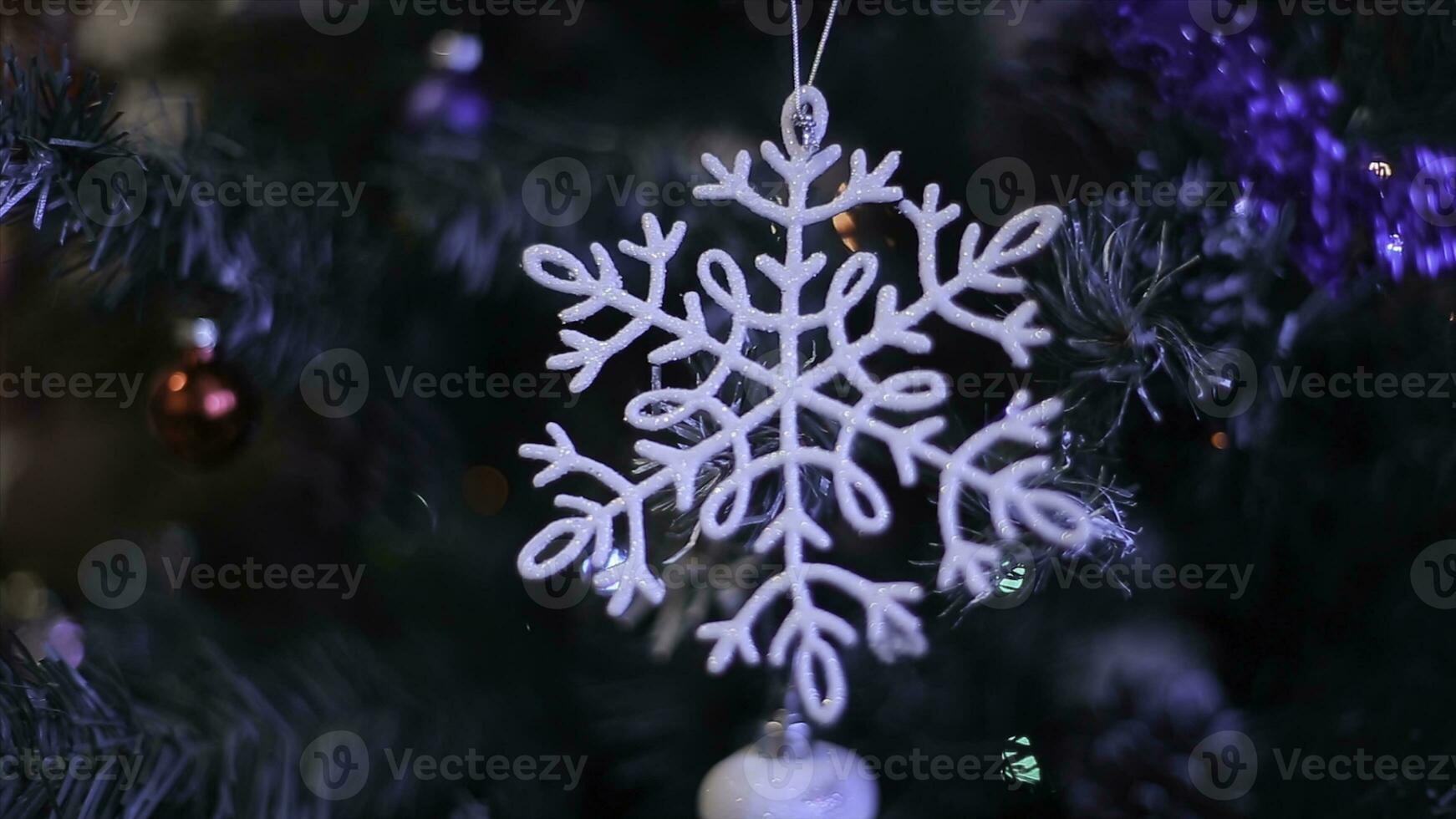 New year's toys on the Christmas tree like snowflake and red balls.New Year's decoration balls on a snowy branch. White snowflake and Blue Christmas ball. Selective focus photo