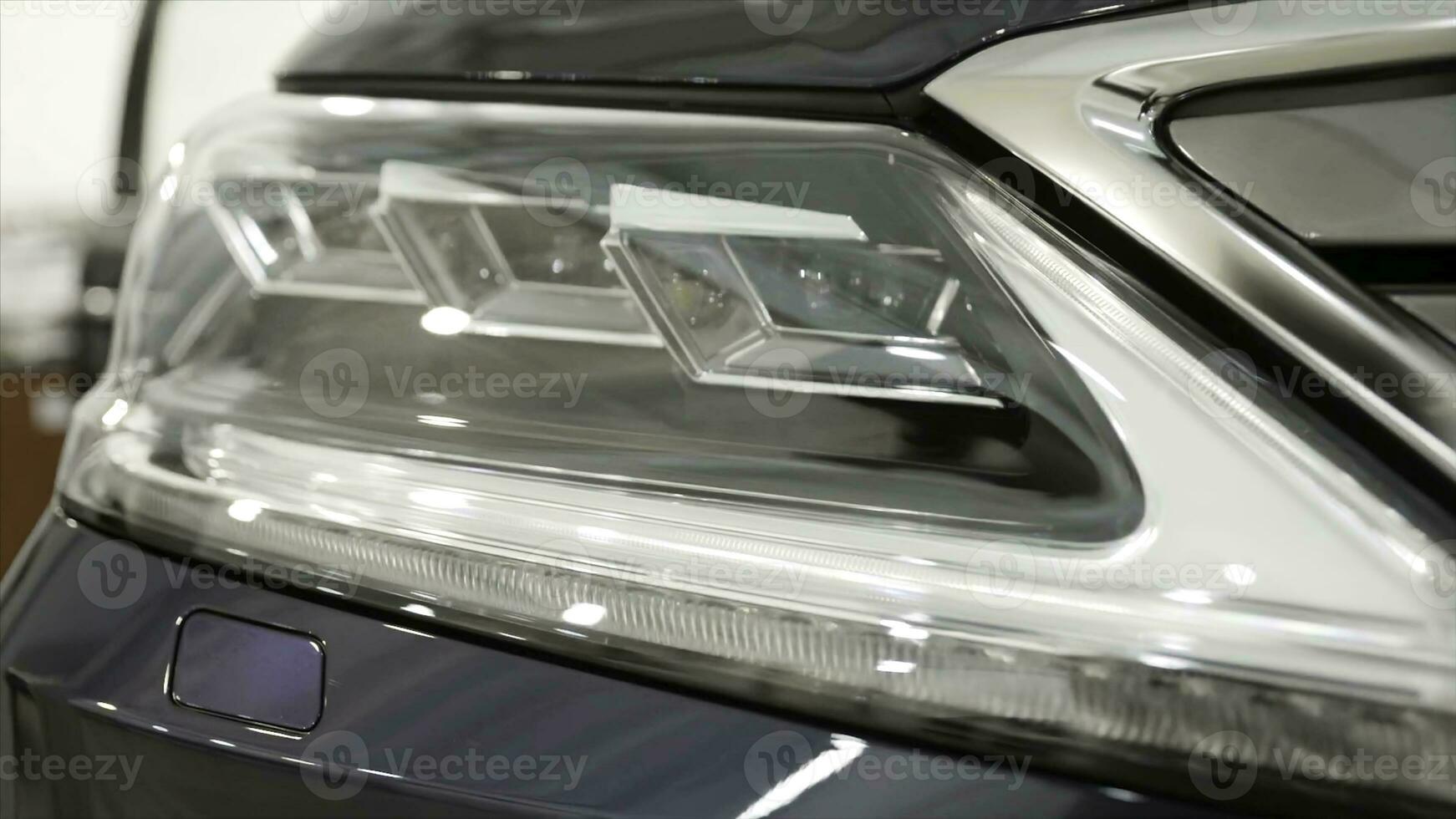 Close up for the headlights of the black new, polished car, luxury concept. Action. Modern car headlights parked in a dealer showroom. photo