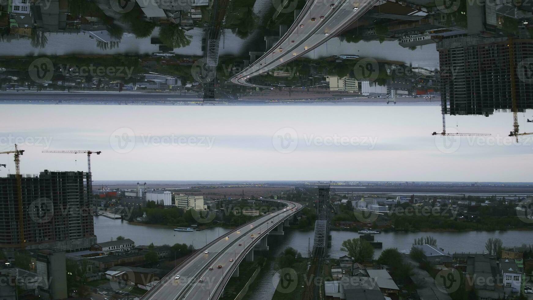 Early morning view of the city with river bridge, unfinished building and many green trees, mirror horizon effect. Media. Grey morning in the city with the turquoise river, ships and the bridge. photo