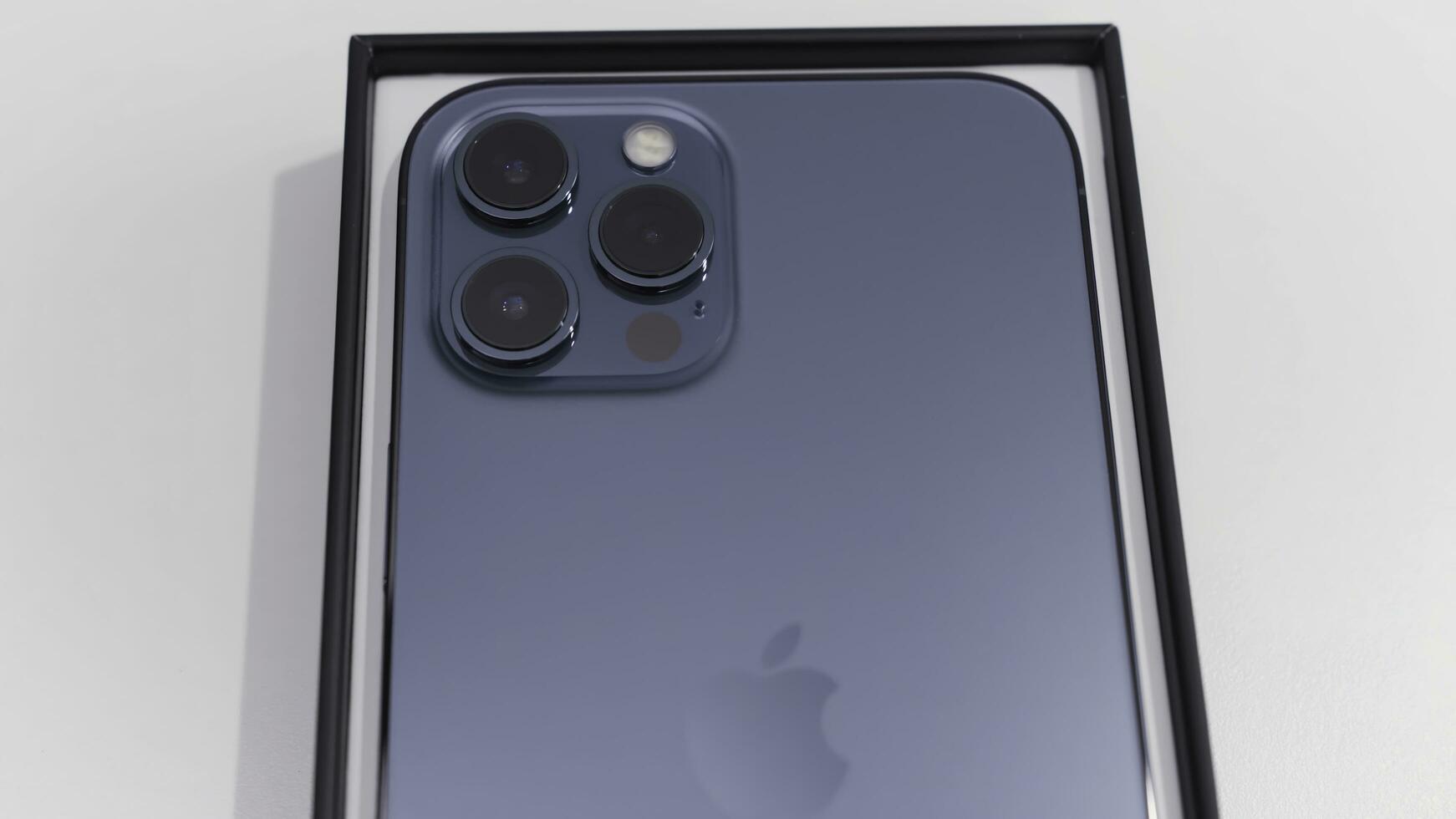 Kiev,Ukraine-11.20.2020. close up of a back view of new smartphone in a box. Action. Newest pacific blue Apple Iphone 12 Pro Max isolated on white background. photo