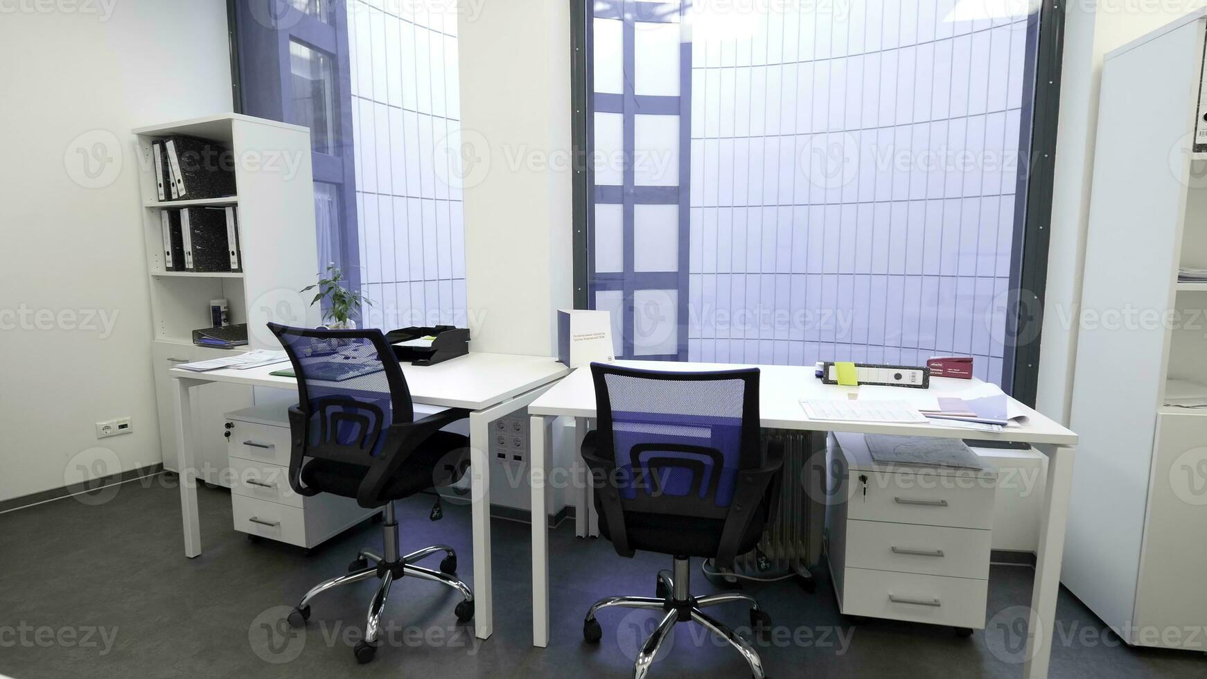 moderno, elegante oficina con panorámico ventanas y lugares de trabajo ligero oficina interior con mesas, sillas y cofres de cajones. foto