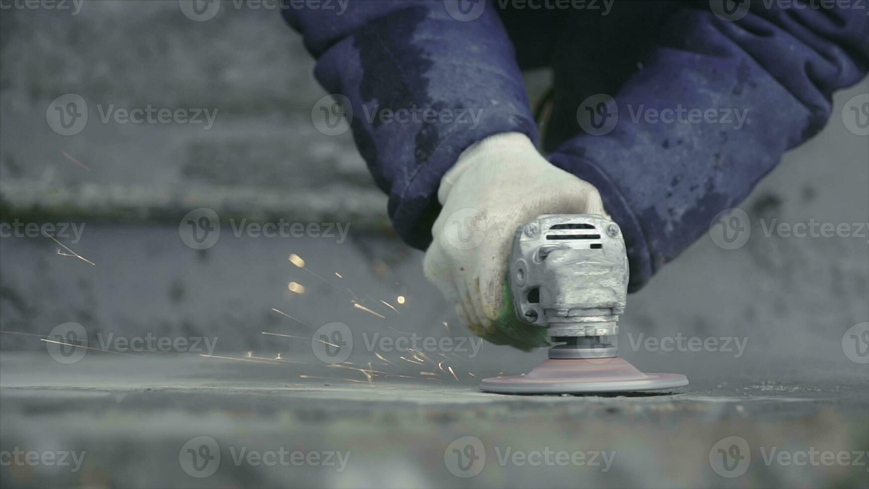 Builder worker with grinder machine cutting finishing concrete wall at construction site. Clip. Worker grinds concrete wall photo