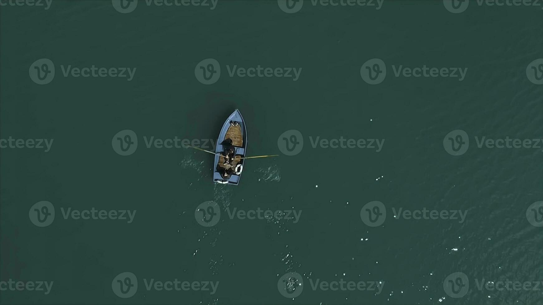 Aerial Boat on the lake. Aerial view on two men in a boat on a lake, rowed to the shore. Lonely boat in the middle of the river, lake. Boat single row on sea with reflection in the water in the photo