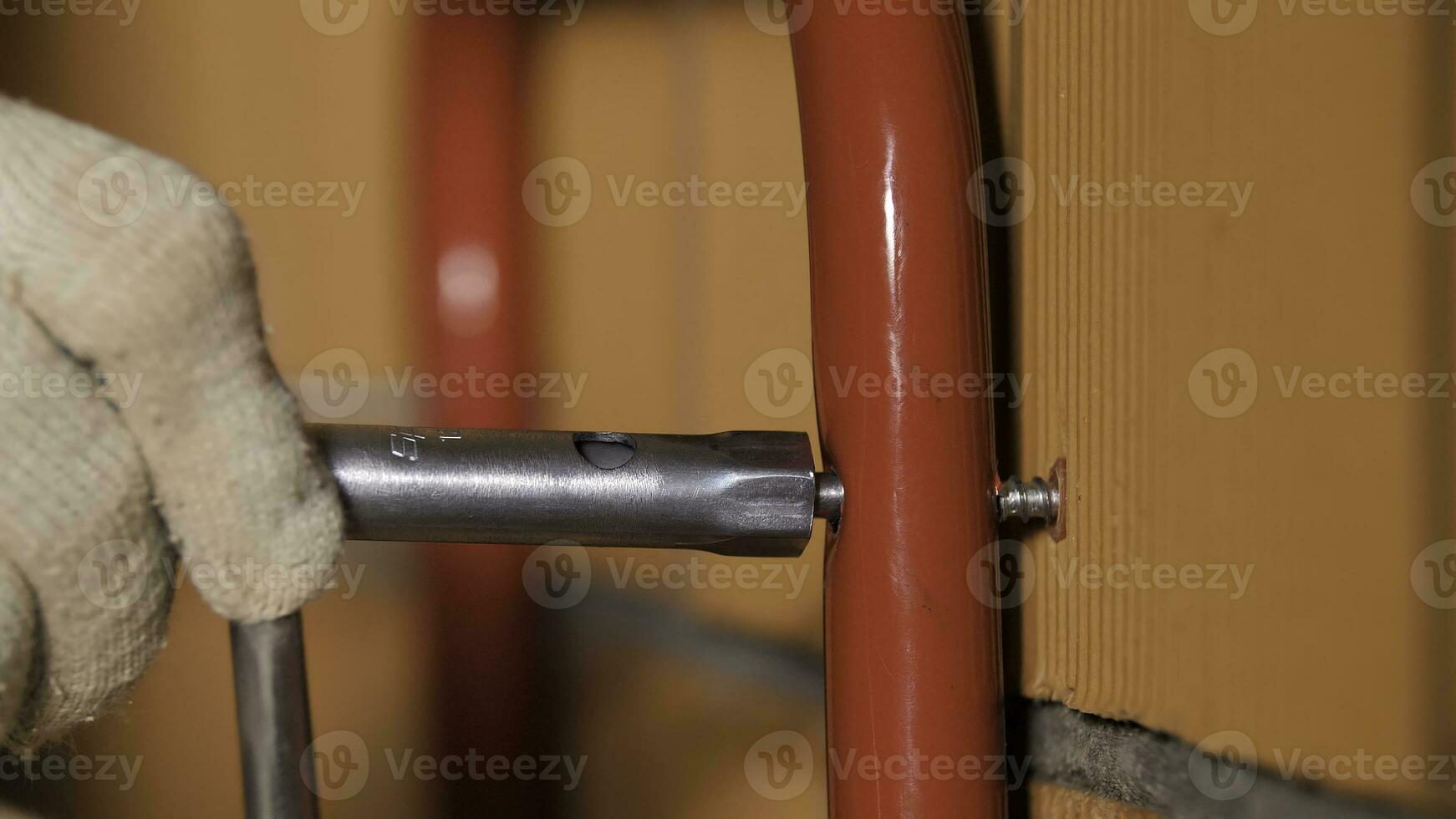 Side view of a man tightening the screw inside the red ceramic blocks. Stock footage. Worker during the process of attaching the metal detail to the wall. photo