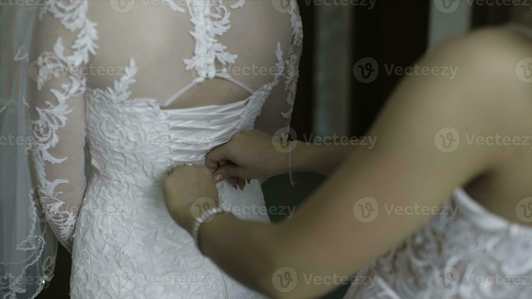 Morning bride. Bridesmaid helping the bride lacing up her dress. Girlfriends help the bride to fasten a dress photo