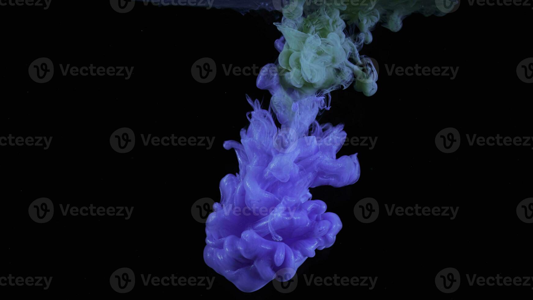 Blue and green inks spreading in water isolated on black background. Stock footage. Breathtaking flow of bright colorful paints looking like jellyfish. photo