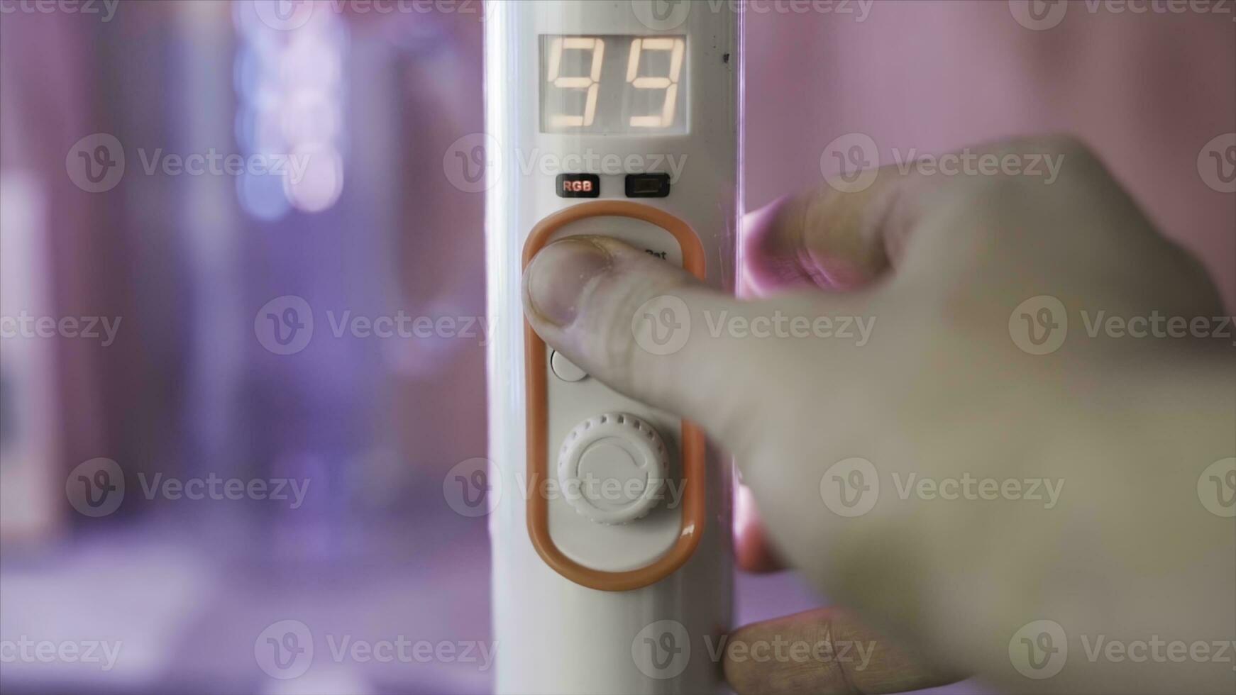 Close up of a hand turning remote controller of LED illumination in the room. Action. Color of light in the room is being changed from pink to purple with a remote controller. photo