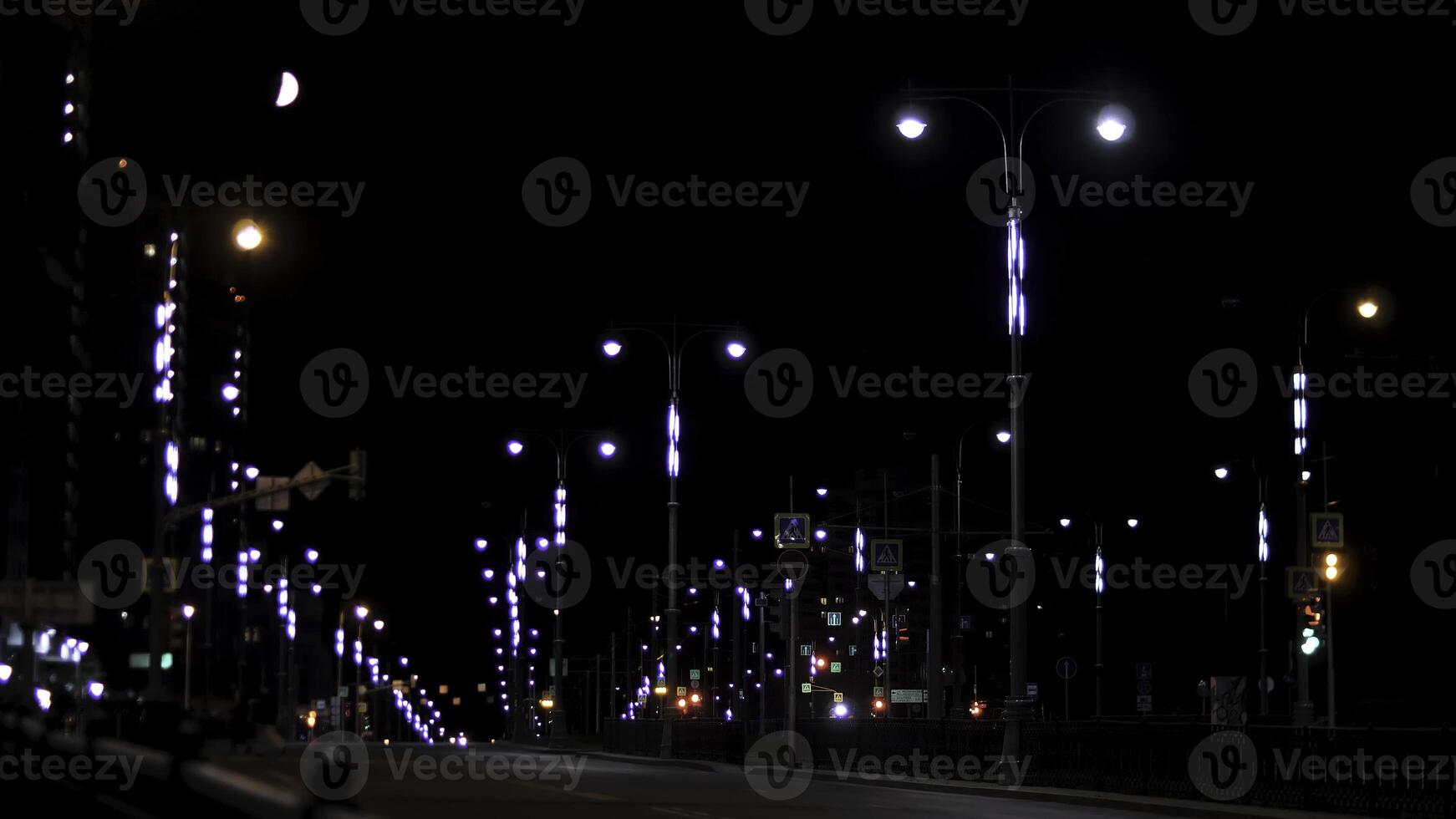 Empty residential street in the late evening with road signs and lanterns on black sky background. Stock footage. Night urban street lit by neon lights. photo
