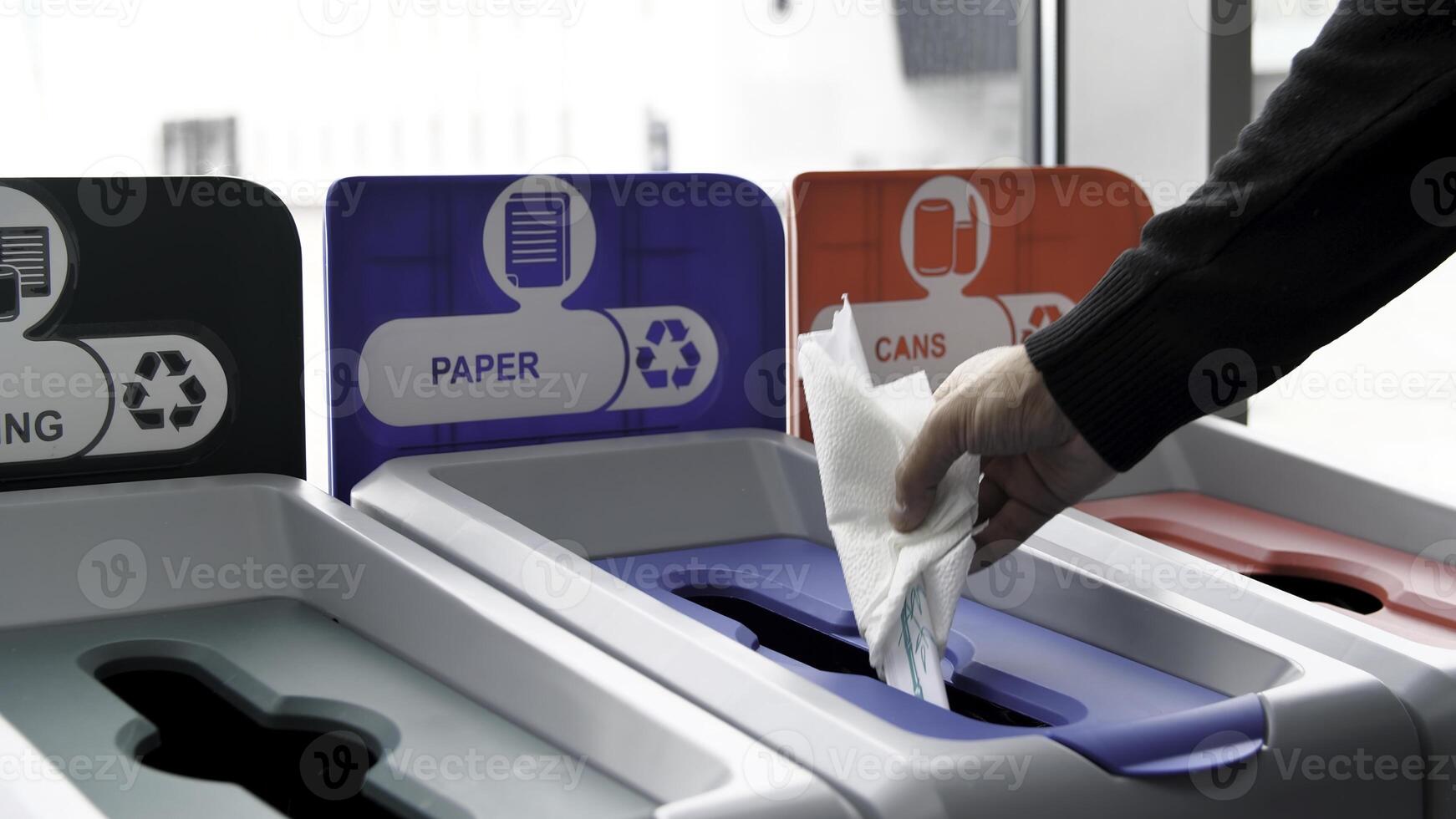 Close up of trash bins of different color for recycling different materials. Media. Male hand throwing paper in recycling bin, concept of ecology, waste separation point for mixed materials, cans, and photo