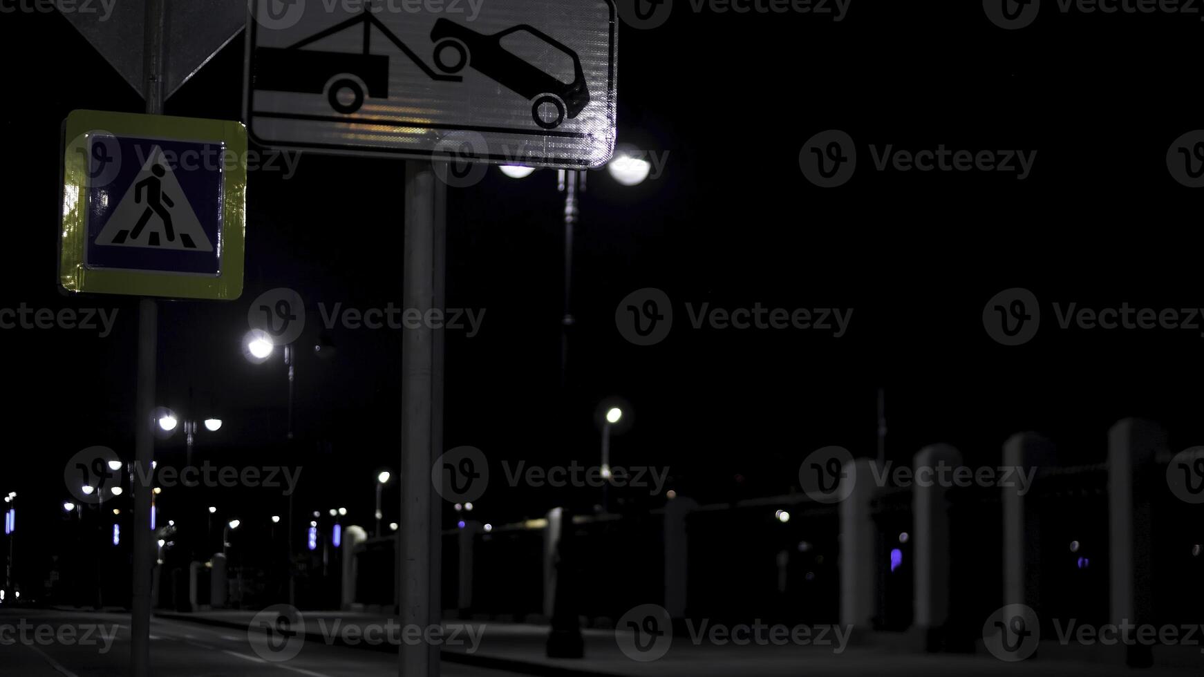 Empty residential street in the late evening with road signs and lanterns on black sky background. Stock footage. Night urban street lit by neon lights. photo