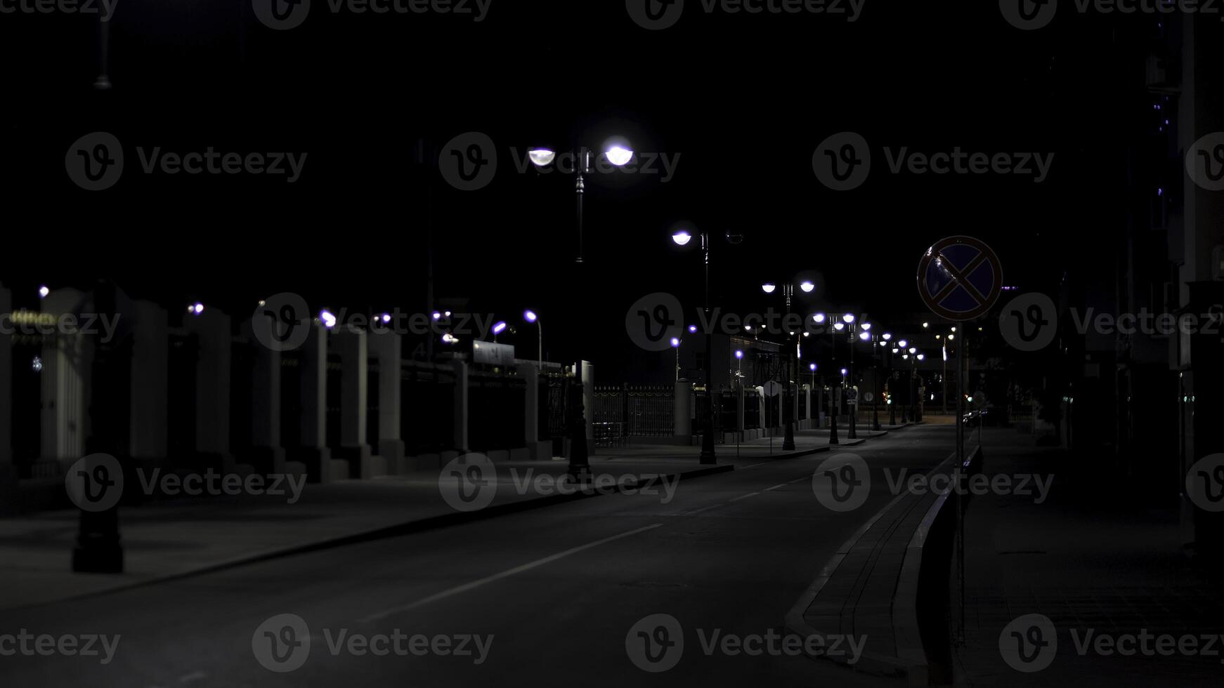 Beautiful and calm atmosphere of the summer night in big city, dark street with many shining lanterns. Stock footage. Empty road and sidewalk. photo