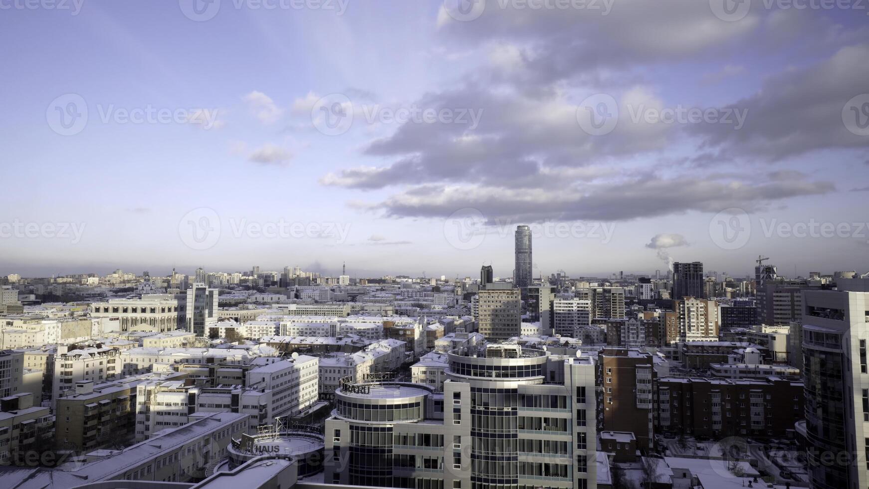 Top view of city panorama with blue sky on horizon. Action. Beautiful day in big city in winter with blue sky and clouds. Urban winter landscape with skyscrapers and simple houses photo