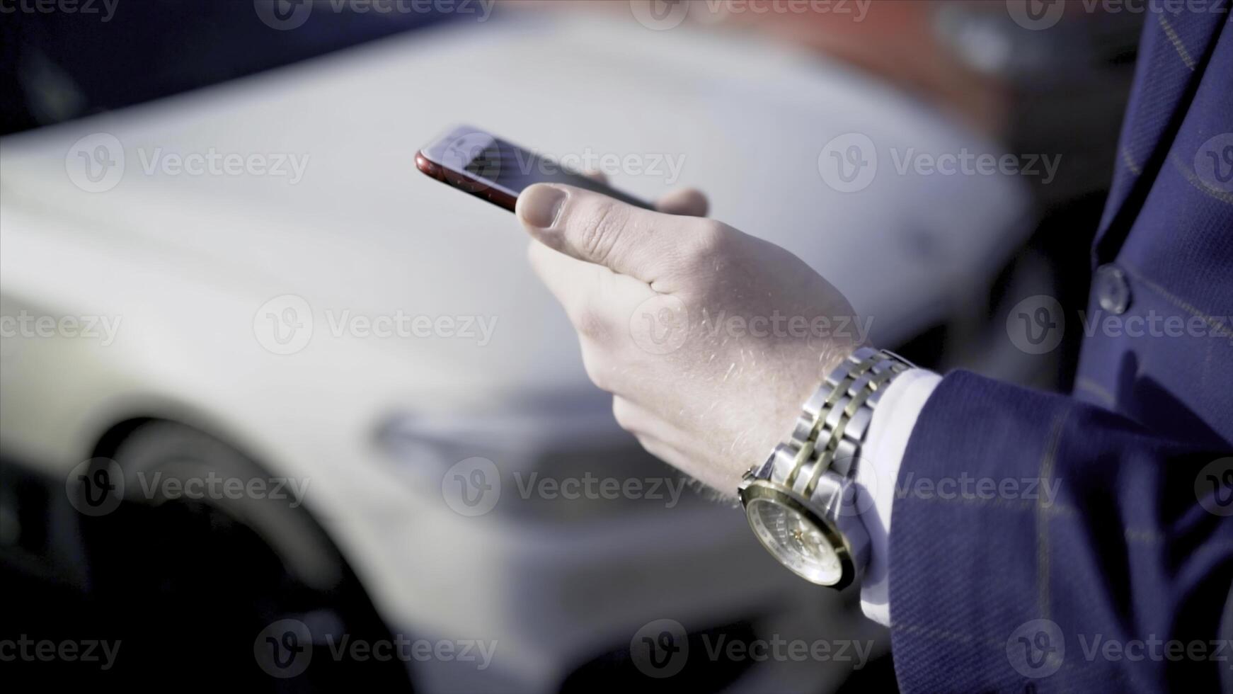 Close-up of businessman pressing car key. Action. Businessman opens car with electronic key and looks at phone. Modern car key to open and start it photo