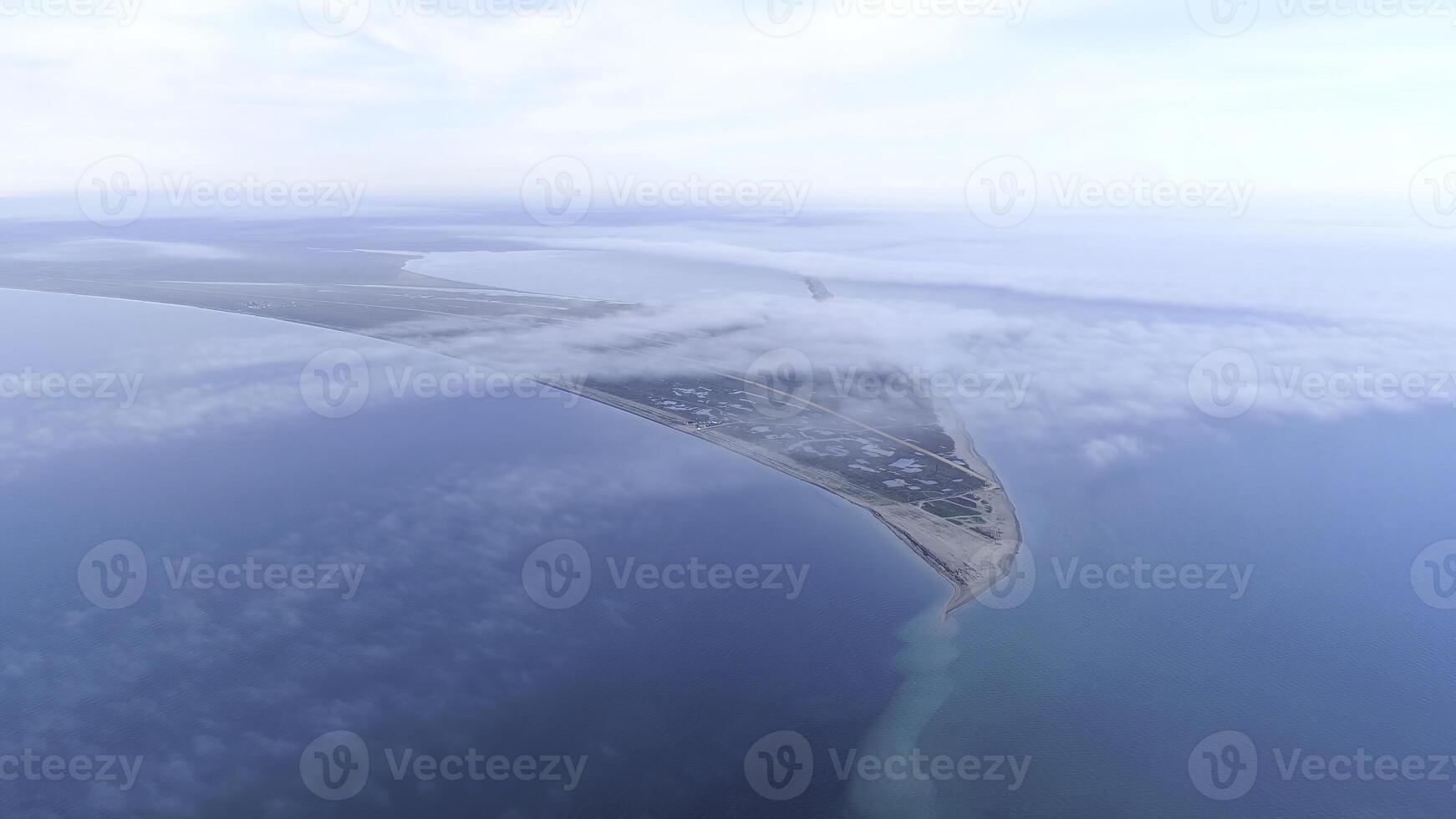 Top view of coast among sea on background of sky horizon. Shot. The highest view in sky among clouds on blue sea and triangular shore photo