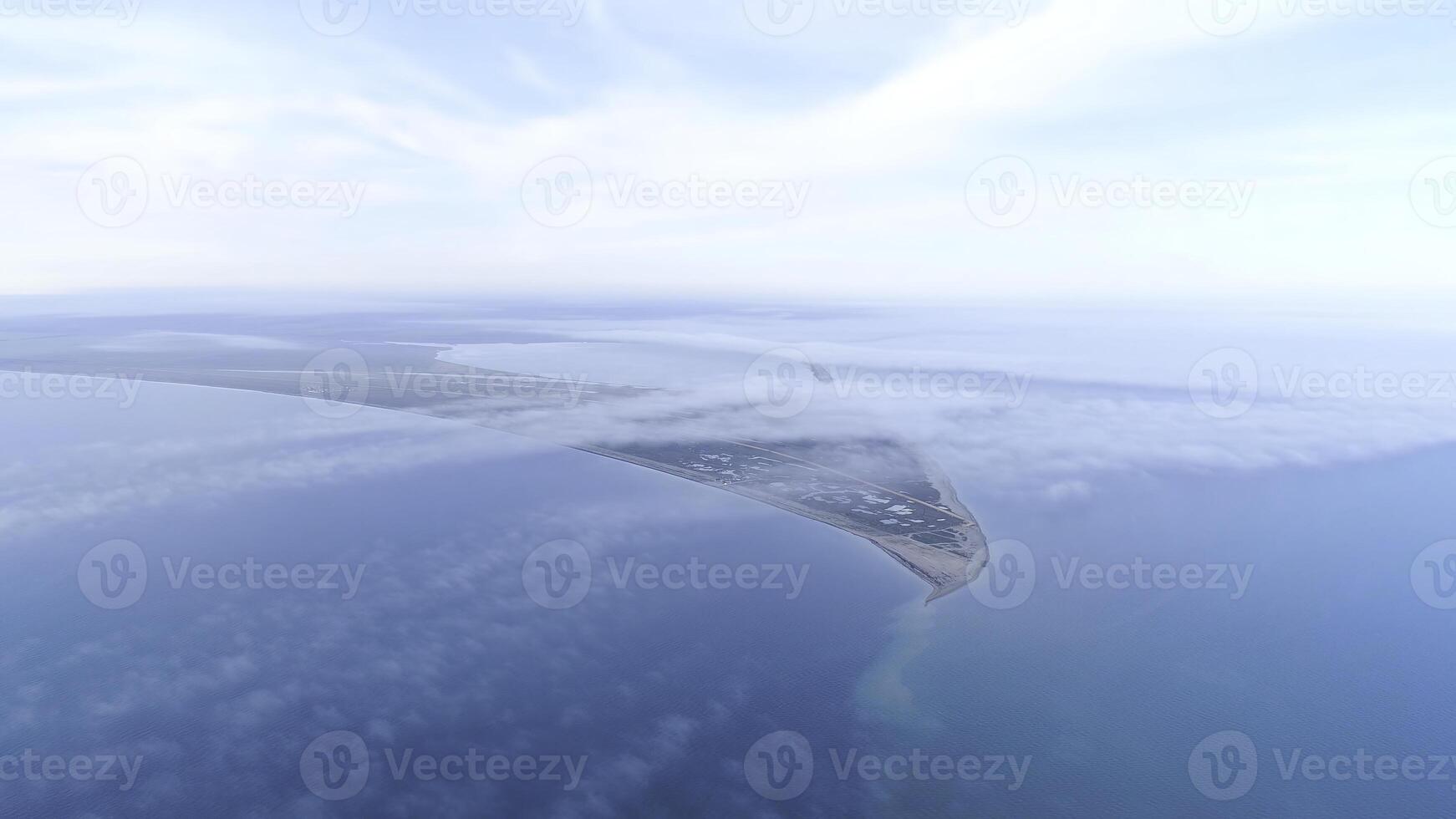 Top view of coast among sea on background of sky horizon. Shot. The highest view in sky among clouds on blue sea and triangular shore photo