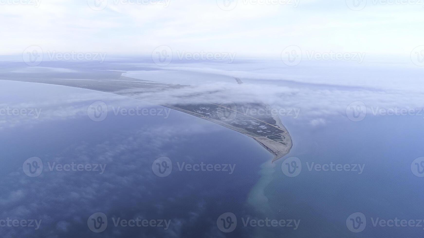 Top view of coast among sea on background of sky horizon. Shot. The highest view in sky among clouds on blue sea and triangular shore photo