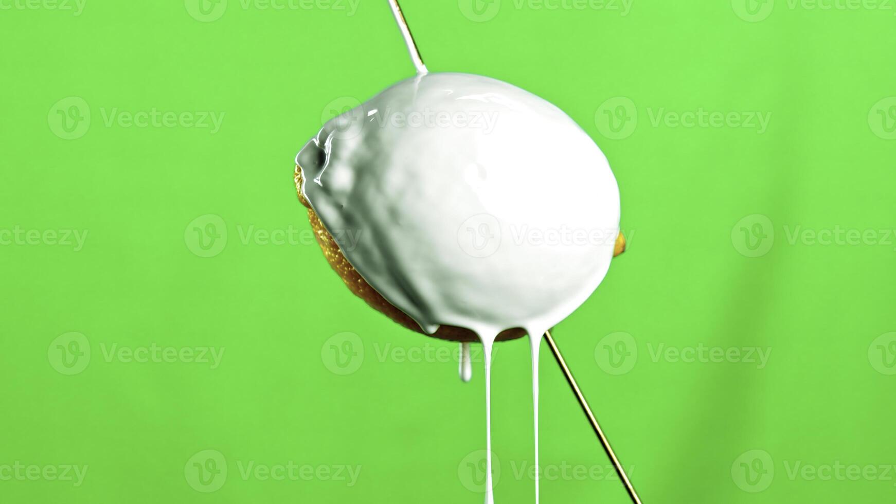 Fresh yellow lemon isolated on a green background. Stock clip. Pouring white paint on a lemon fruit with drops falling down. photo