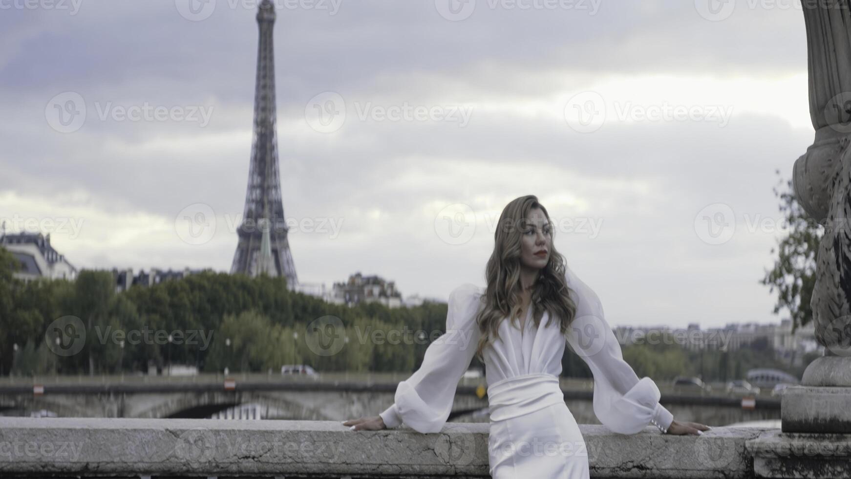 Gorgeous woman in dress on background of Paris. Action. Woman in elegant white dress on background of Eiffel Tower. Beautiful elegant woman in dress on street of Paris photo