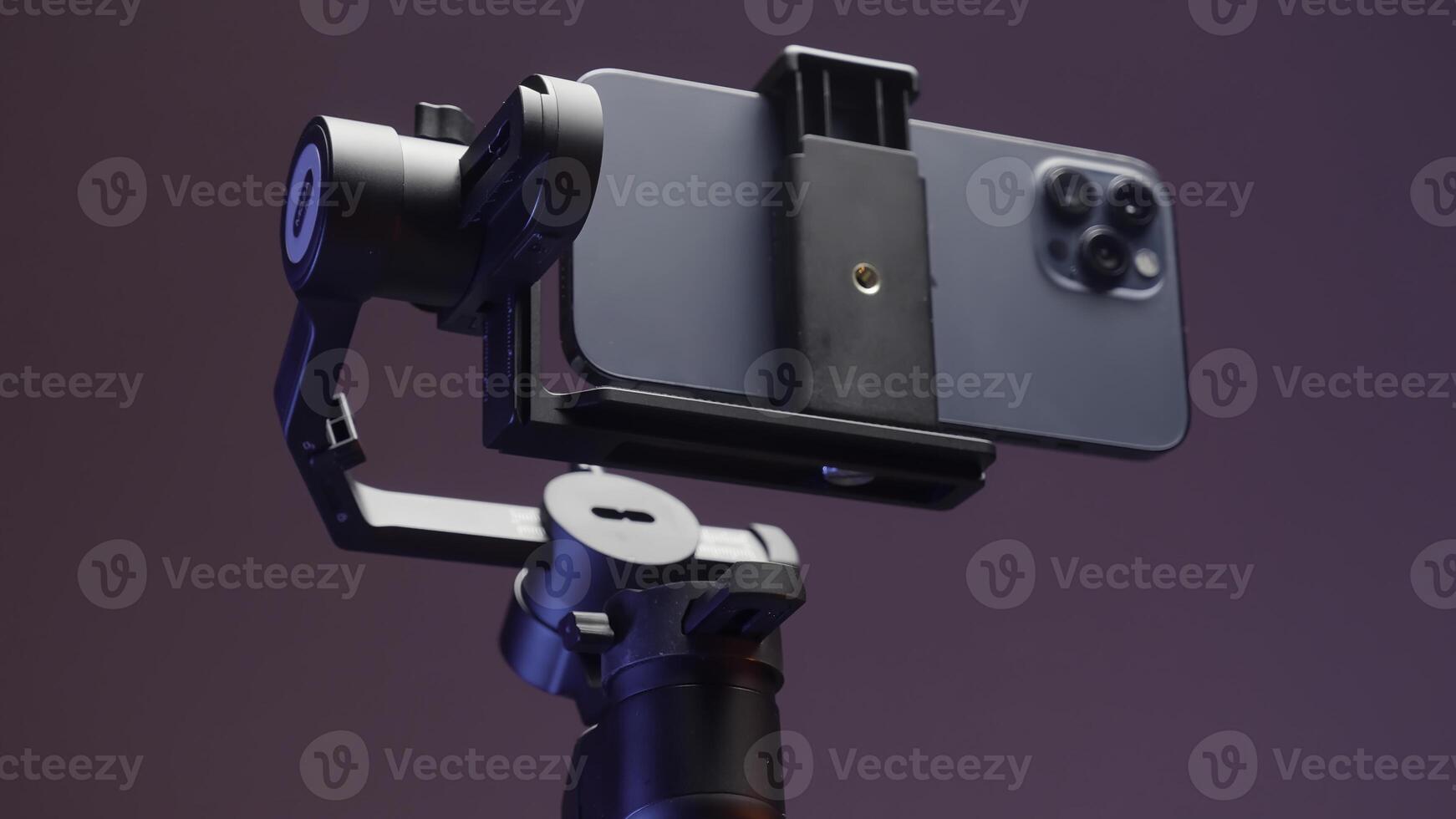 Stabilizer for the smartphone with three cameras isolated on a pink wall background. Action. New professional steadicam for shooting and a phone. photo