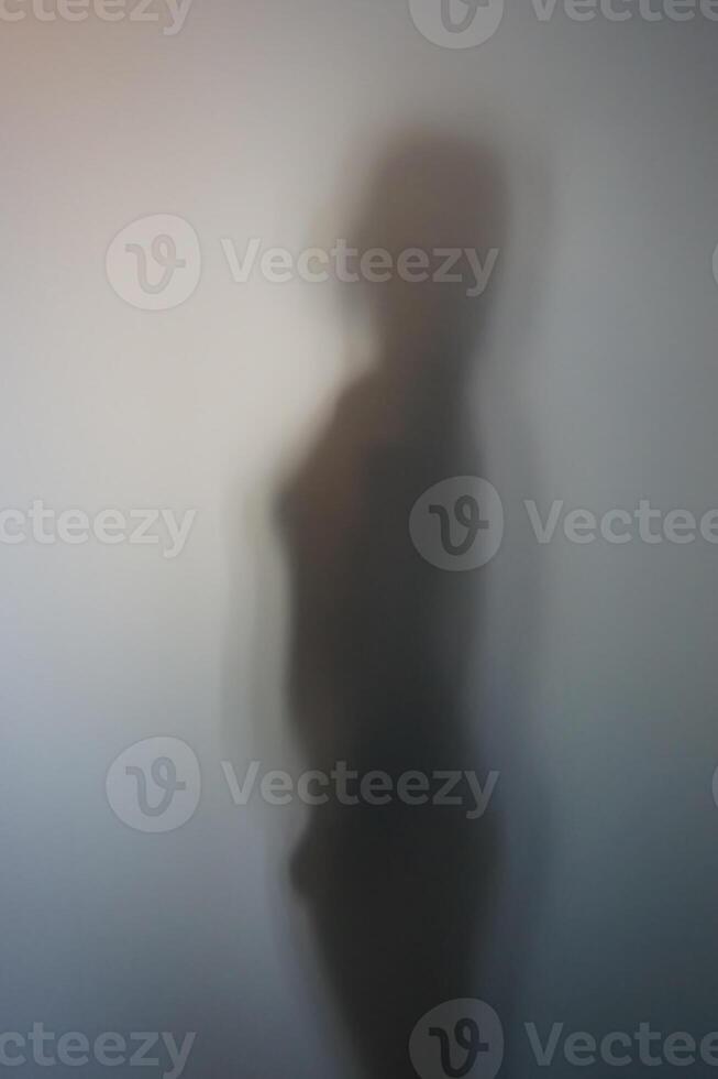 Side View of Woman Silhouette Behind Frosted Glass photo