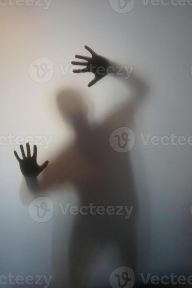 Man with Raised Hands Silhouette Behind Frosted Glass photo